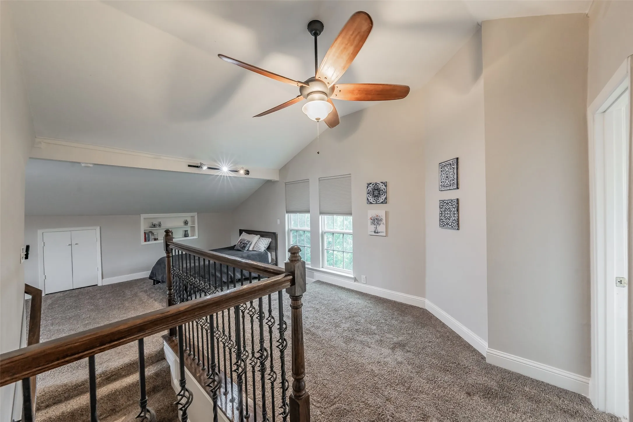 Carpeted loft area featuring a vaulted ceiling with a wooden ceiling fan