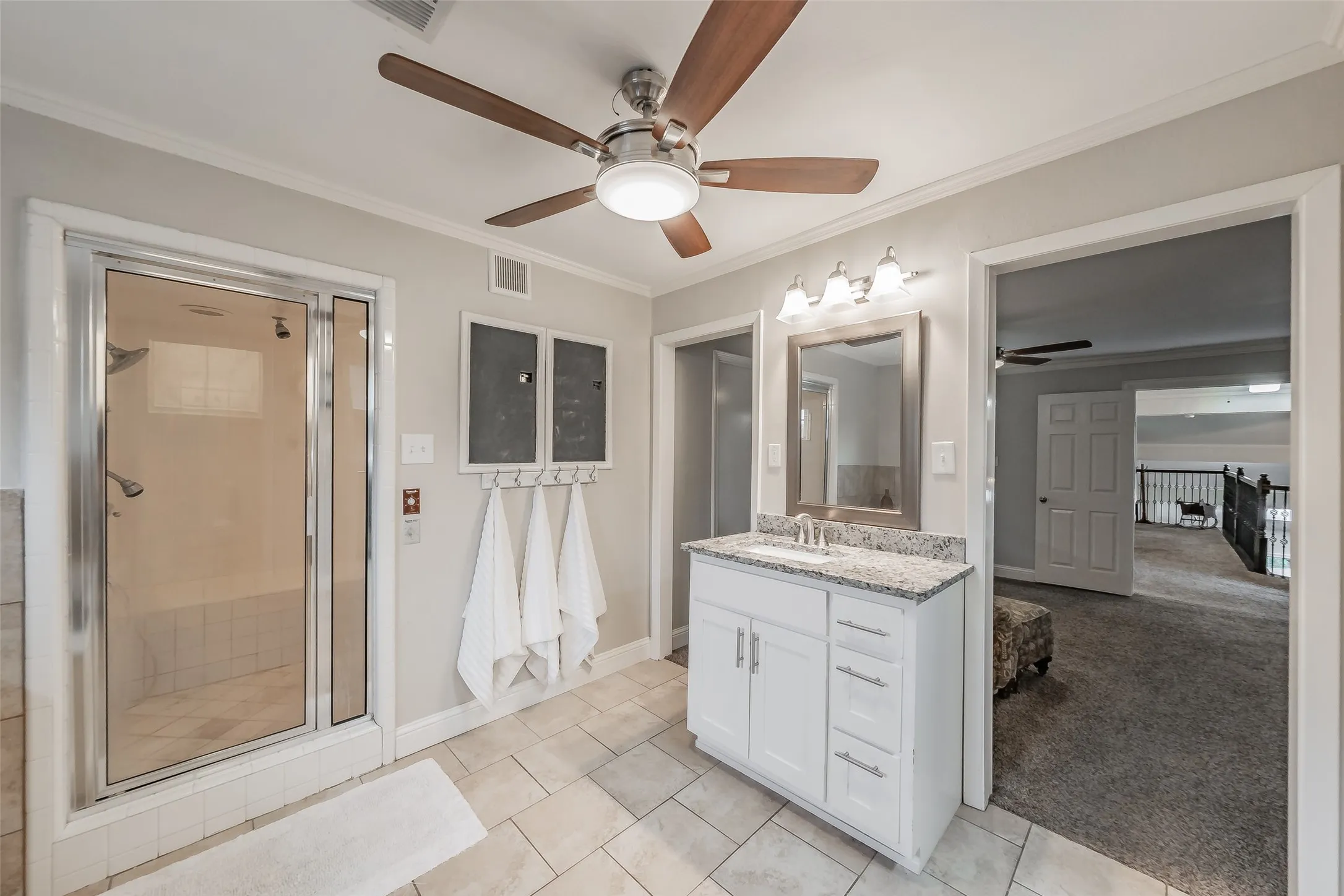 Bathroom featuring a glass-enclosed shower, single vanity with granite countertop, tiled flooring, and a ceiling fan with integrated lighting