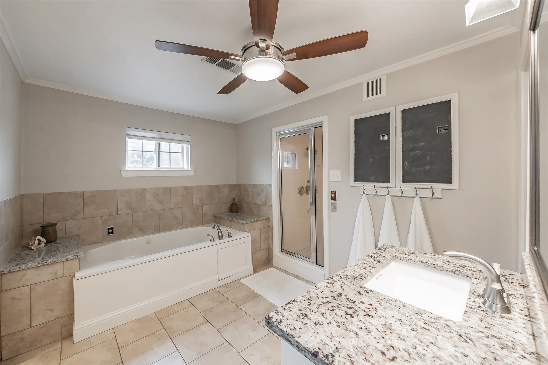 Bathroom featuring a jetted tub with tiled surround, a separate glass-enclosed shower, and a vanity with a white rectangular sink and speckled countertop