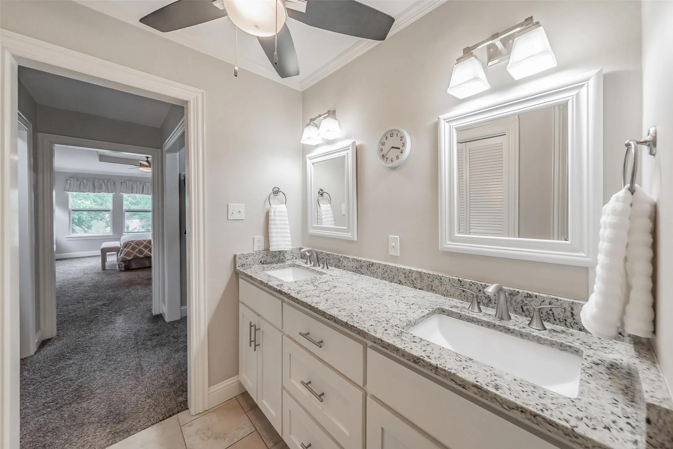 Bathroom featuring a dual vanity with white cabinetry and granite countertops, undermount sinks, and framed mirrors