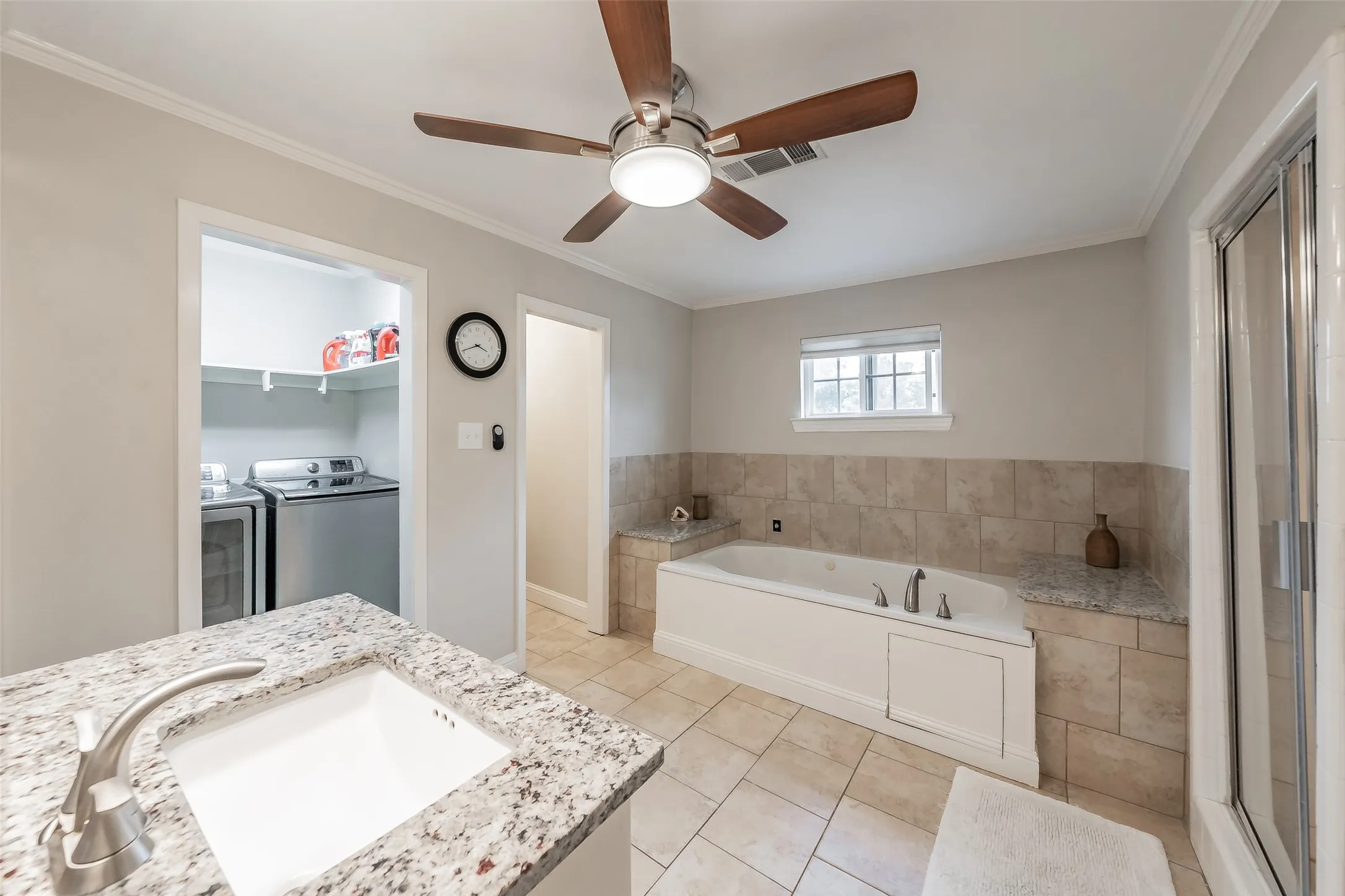 Bathroom featuring a built-in soaking tub with surrounding tile and a granite countertop, a glass-enclosed shower, and a vanity with an integrated sink and granite countertop