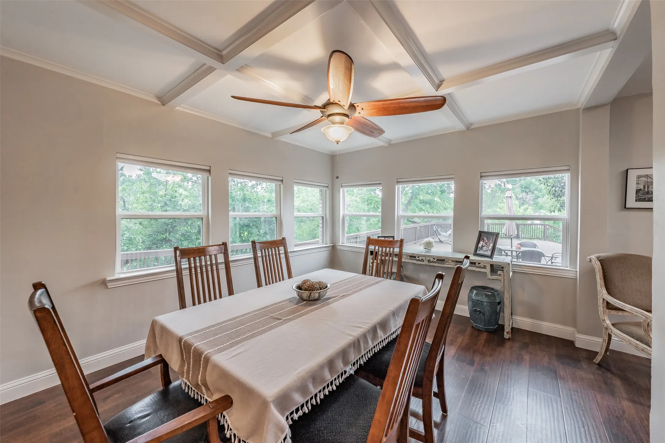 Dining space featuring extensive window lines, coffered ceiling, wood-finish flooring, and a ceiling fan