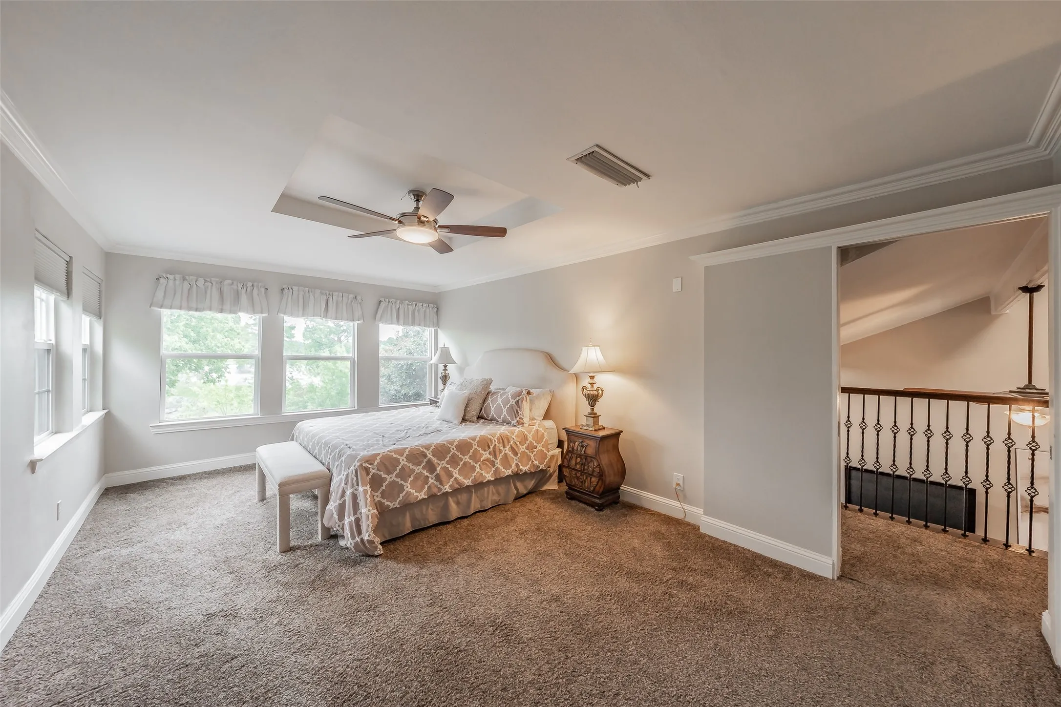 Bedroom featuring wall-to-wall carpeting, multiple windows, a ceiling fan, and crown molding
