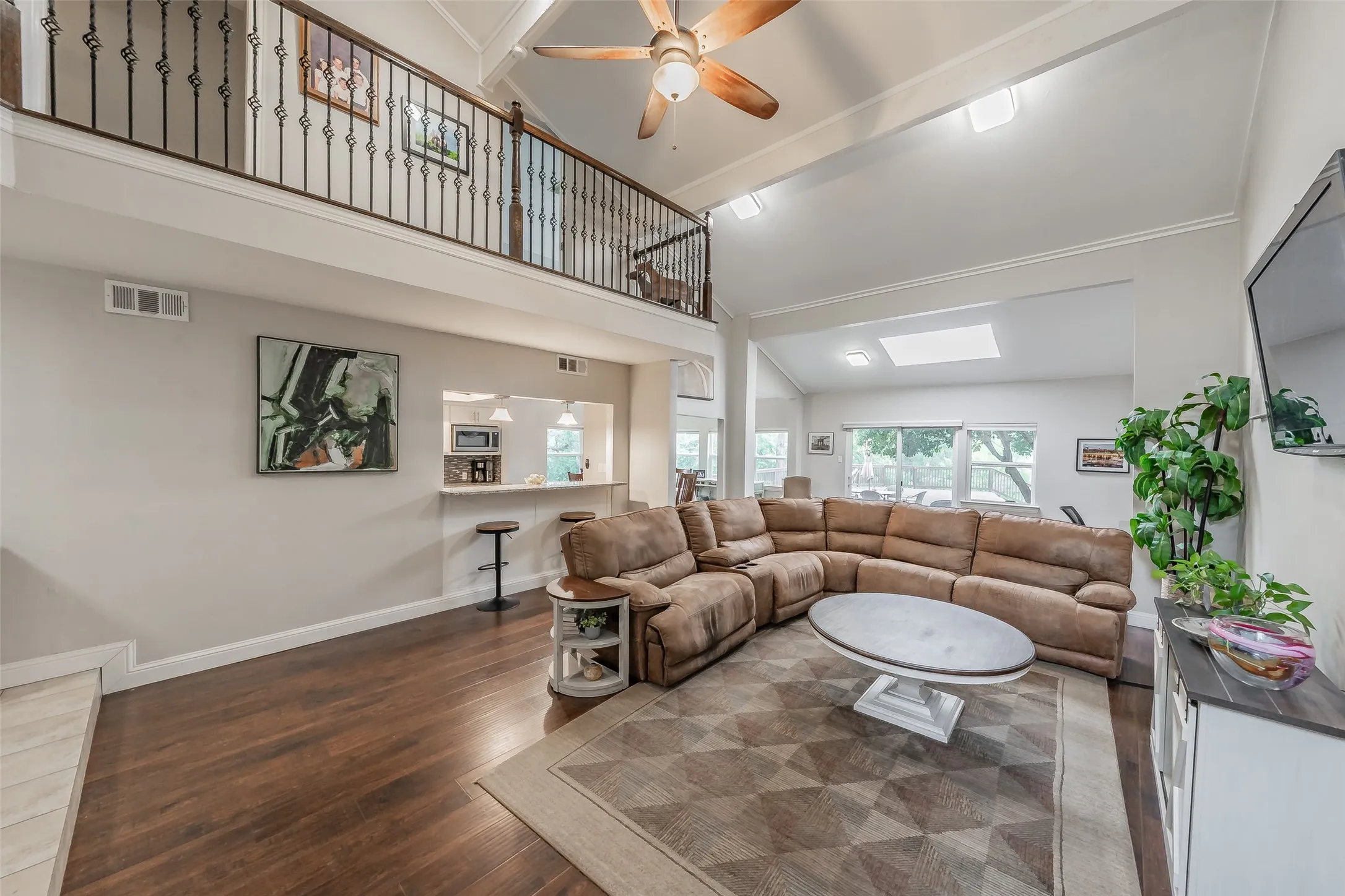 Spacious living area featuring wood-finish flooring, a vaulted ceiling with a fan, and an open concept layout