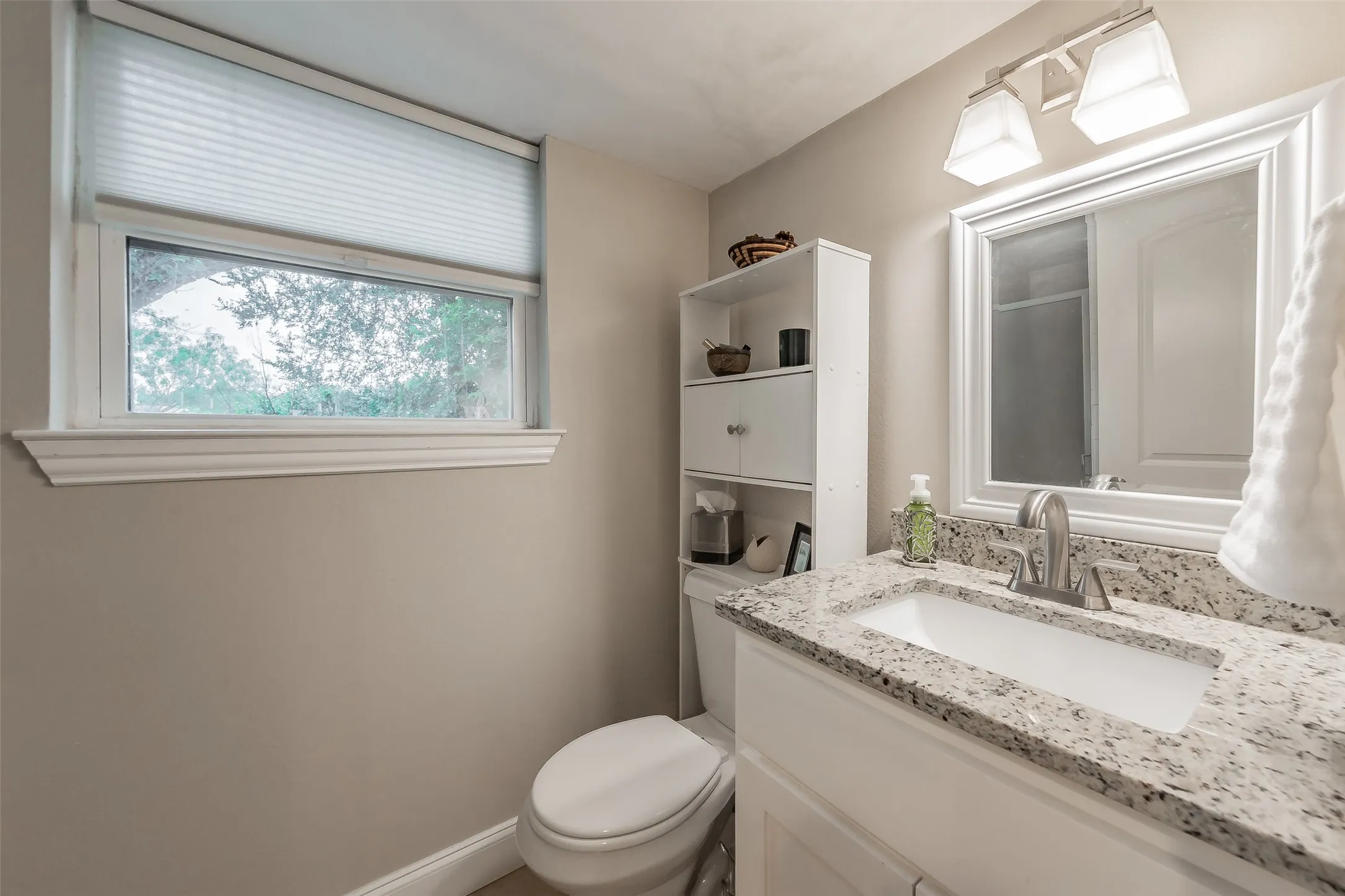 Bathroom featuring a white vanity with a granite-style countertop and an undermount sink