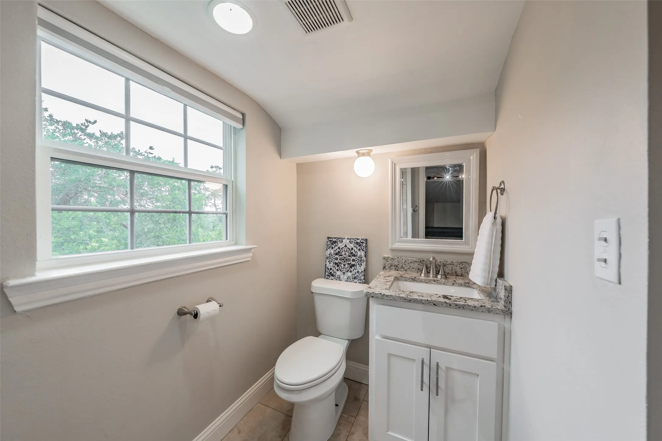 Bathroom featuring a white vanity with a granite-style countertop, undermount sink, and polished chrome faucet