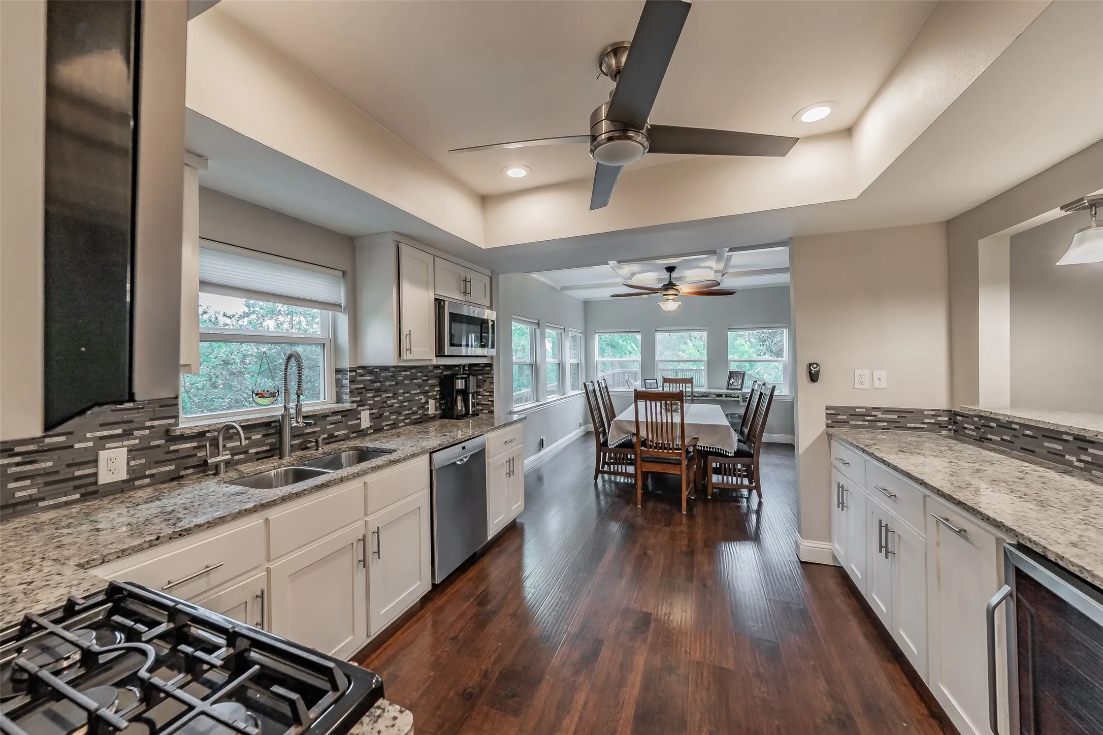 Open concept kitchen featuring recessed lighting, a ceiling fan, white cabinetry, granite countertops, and wood-finish flooring