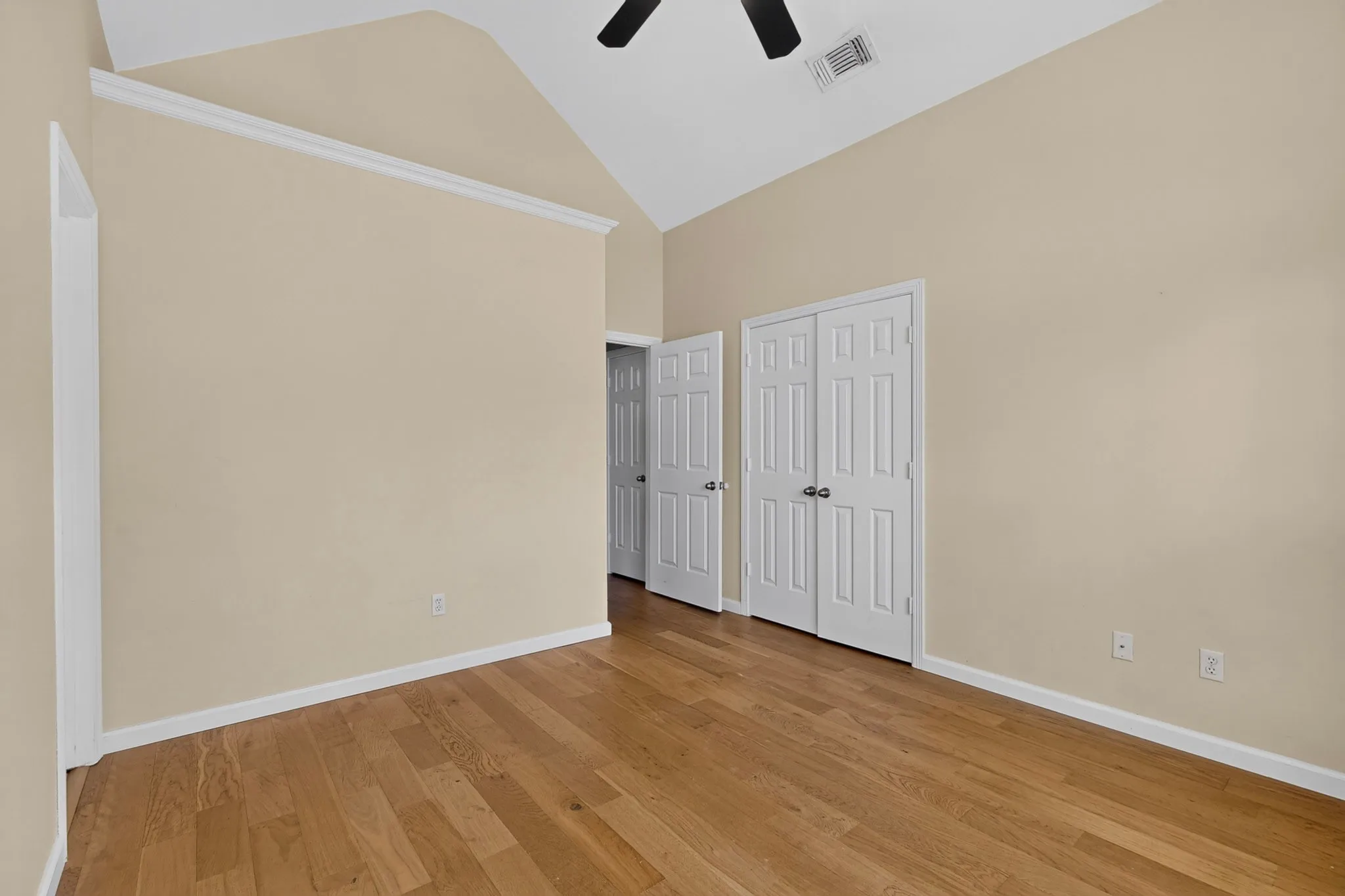 Room featuring vaulted ceilings with a ceiling fan, wood-finish flooring, and light neutral wall paint