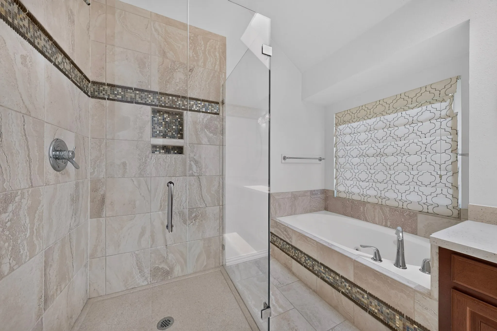 Walk-in shower with natural stone-look tiling and mosaic accents