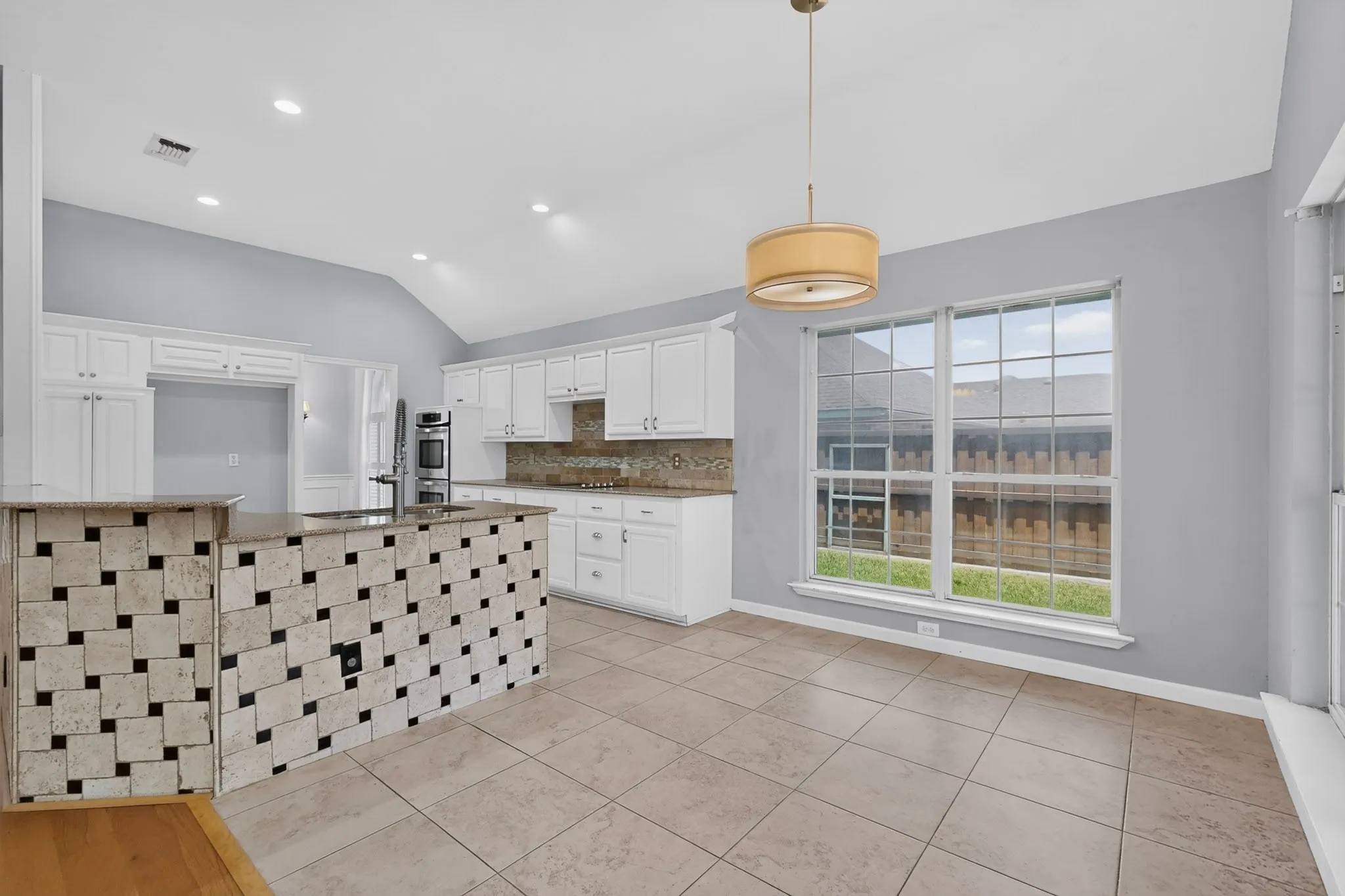 Kitchen featuring white cabinetry, light-toned tile flooring, vaulted ceiling, and recessed lighting