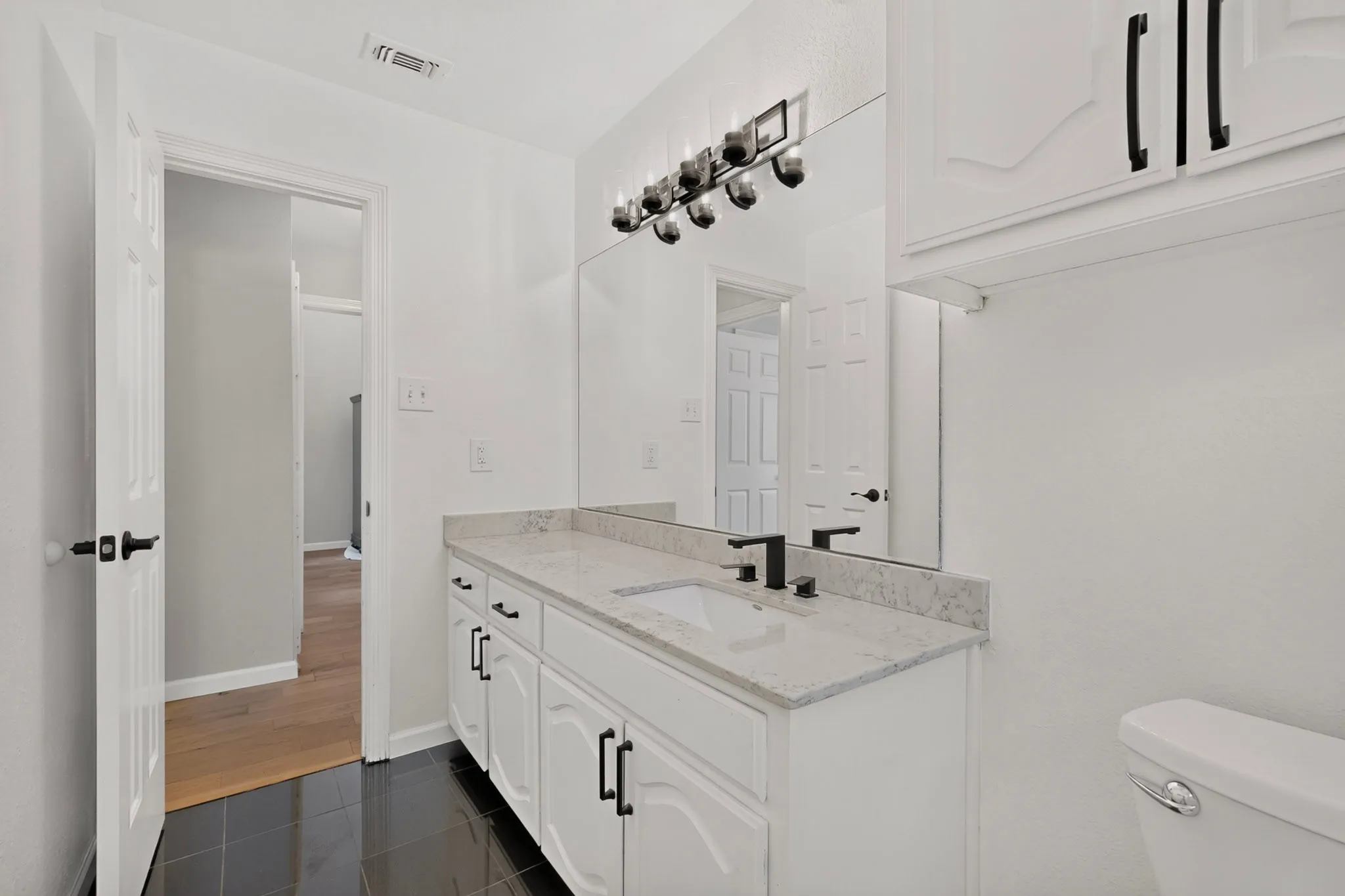 Bathroom featuring a white vanity with panel-front cabinetry, a light-toned countertop, and an integrated sink