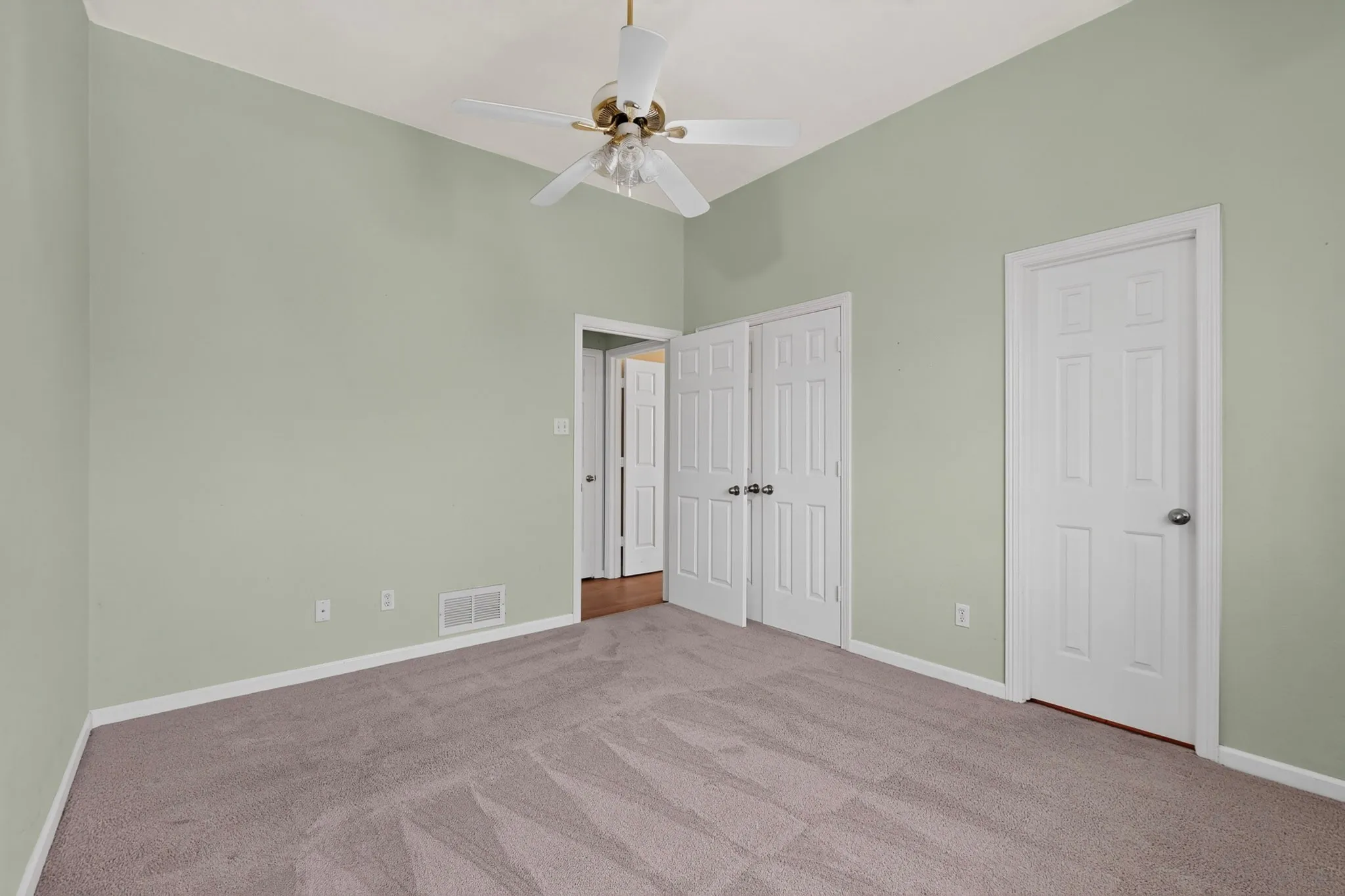 Vaulted ceiling room featuring light green walls, a ceiling fan, and grey carpeting