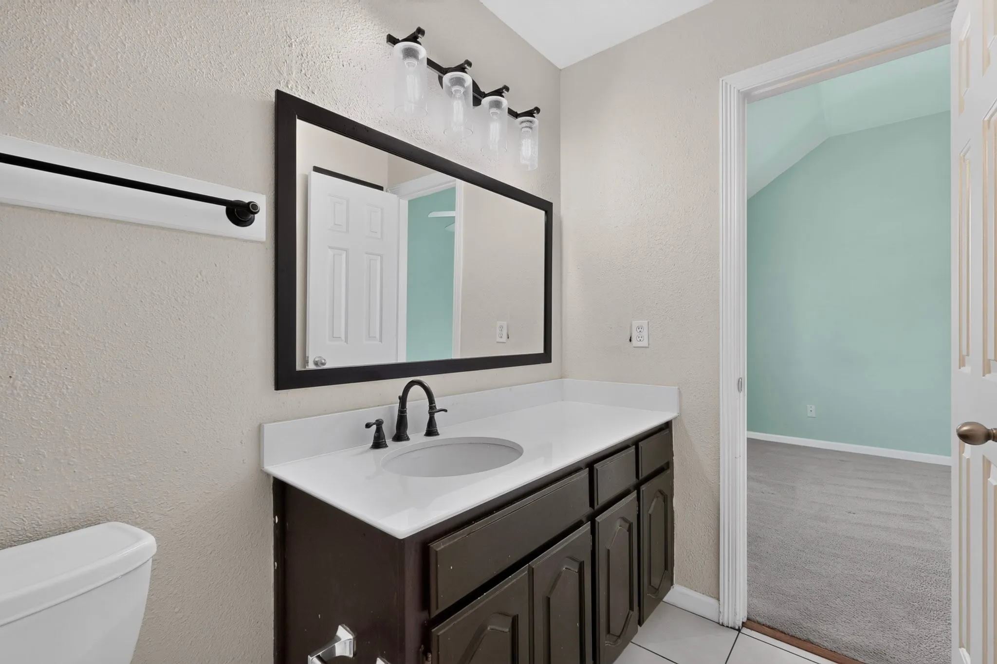 Bathroom featuring a dark wood-finish vanity with a white countertop and integrated sink