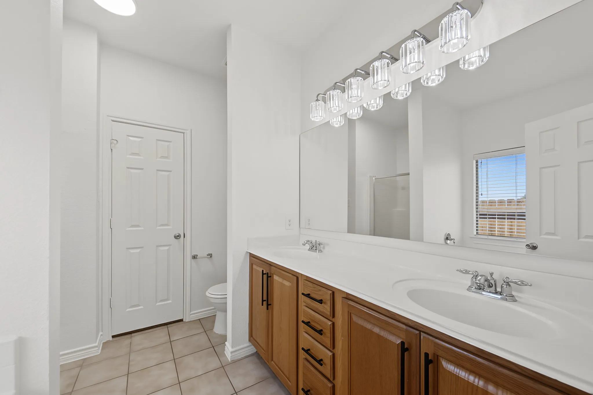 Dual vanity featuring wood-finish cabinetry and chrome hardware