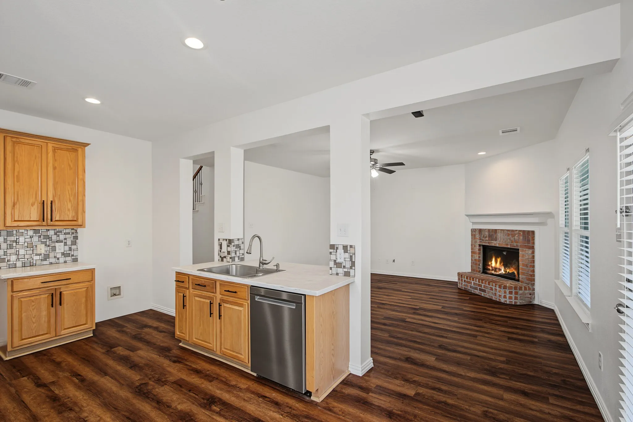 Kitchen with wood-finish flooring, light wood cabinetry, and a stainless steel dishwasher