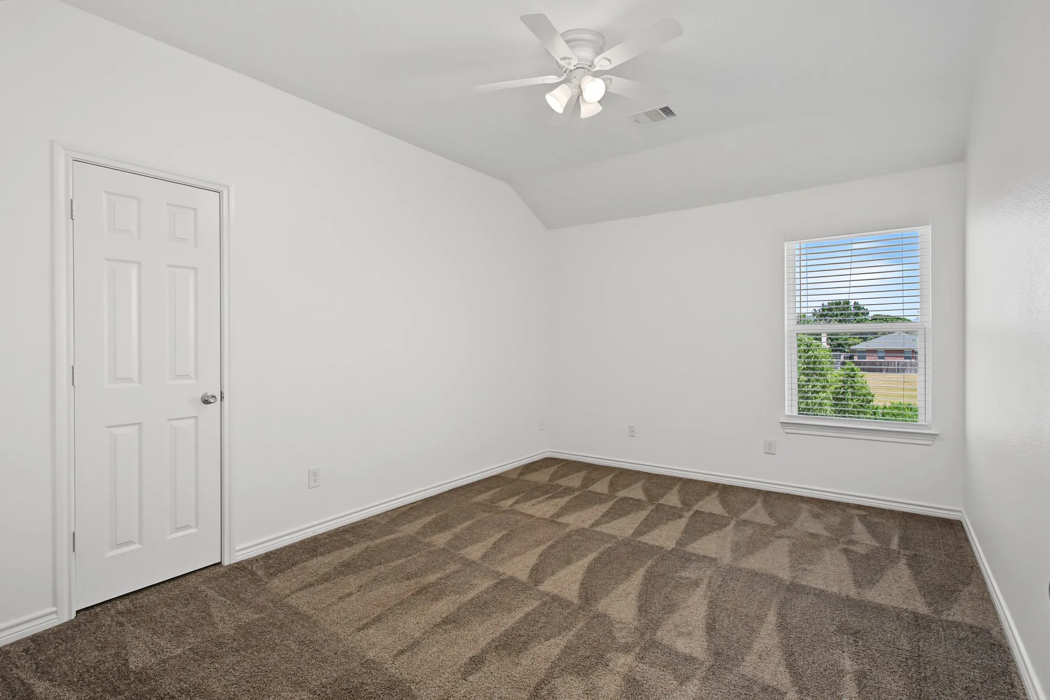 Carpeted room with a ceiling fan