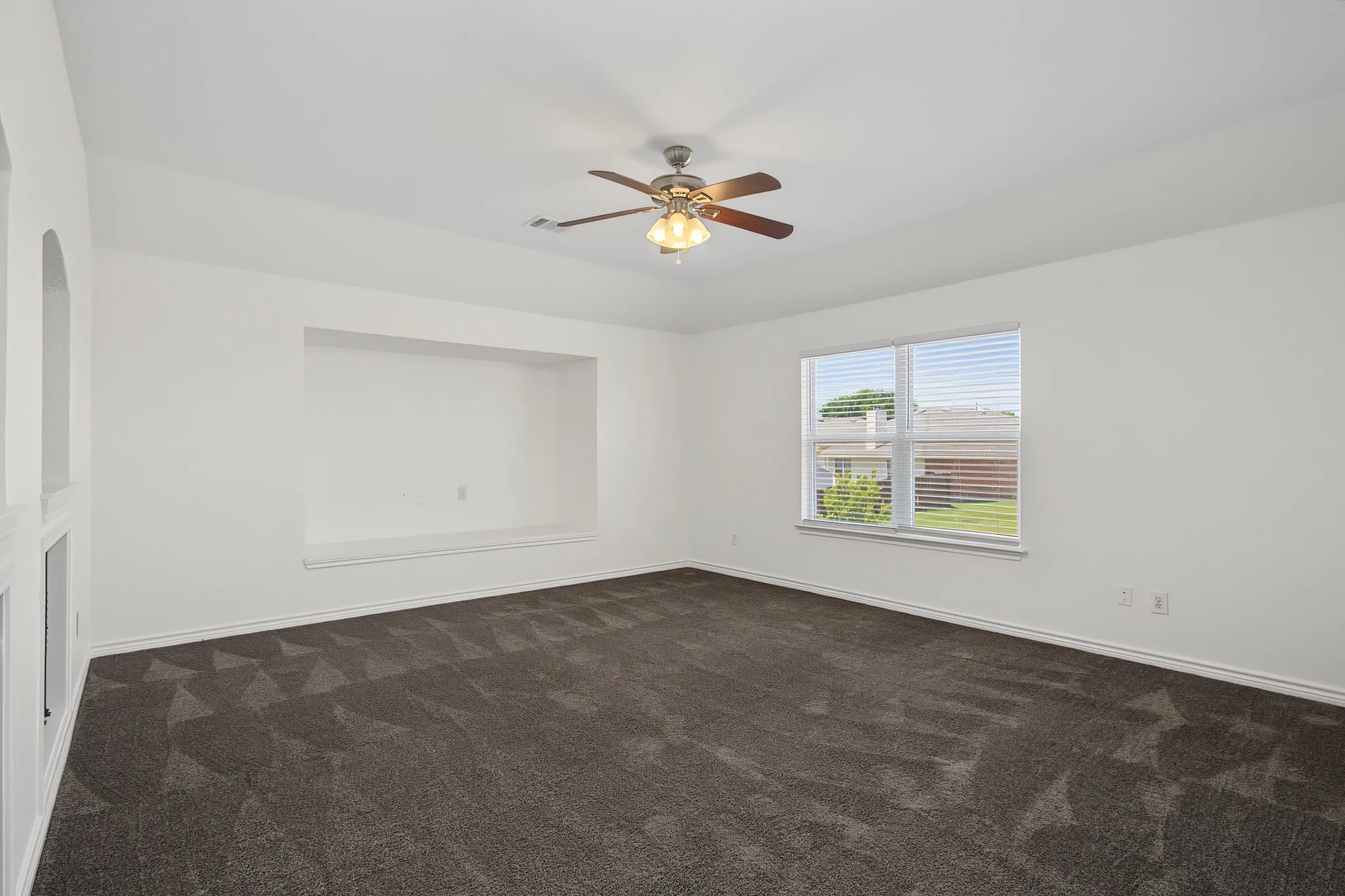 Spacious room featuring patterned carpeting, recessed wall niche, and built-in arched alcoves