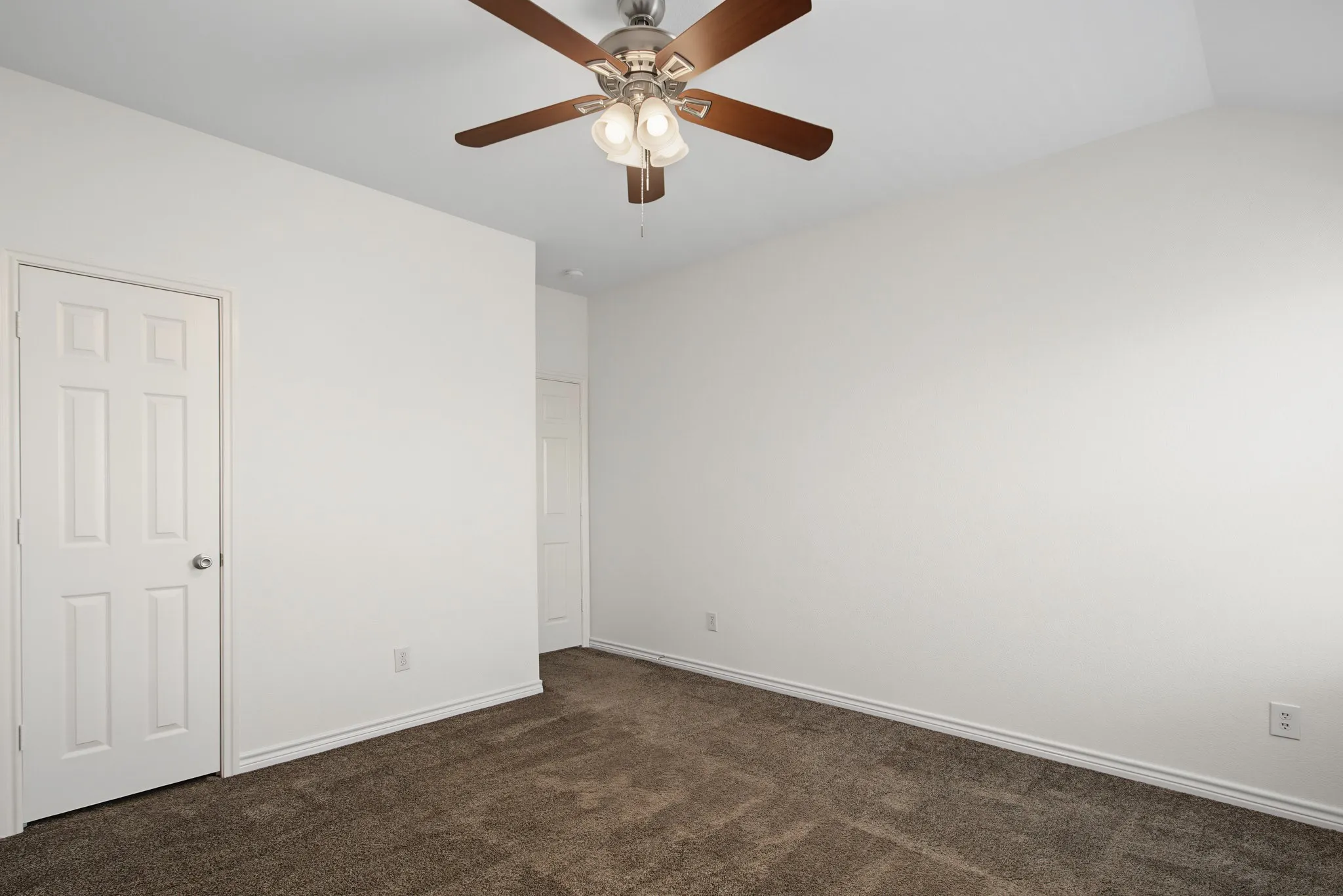 Interior room featuring neutral wall paint, brown carpet, white trim, and a ceiling fan with light fixture