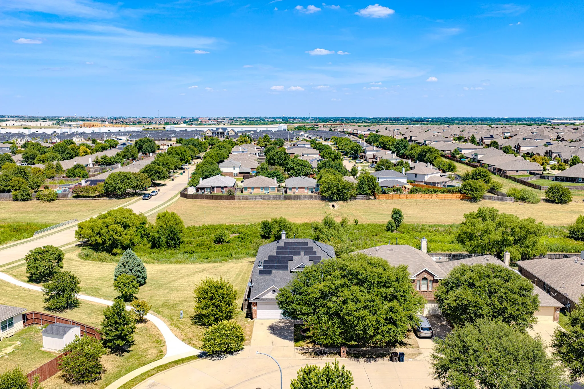 Residential neighborhood featuring numerous single-family homes, mature trees, and unlandscaped open areas