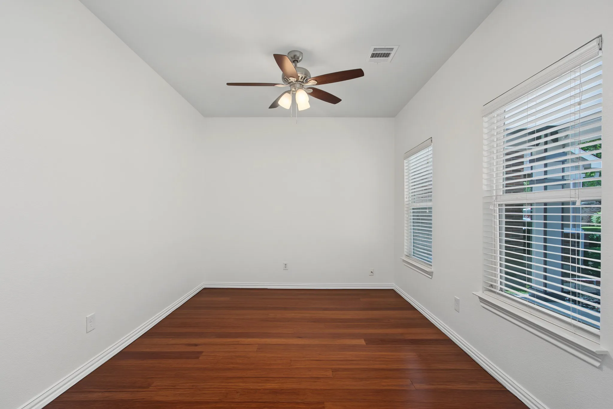Room featuring rich wood-finish flooring, white baseboards, and bright white walls