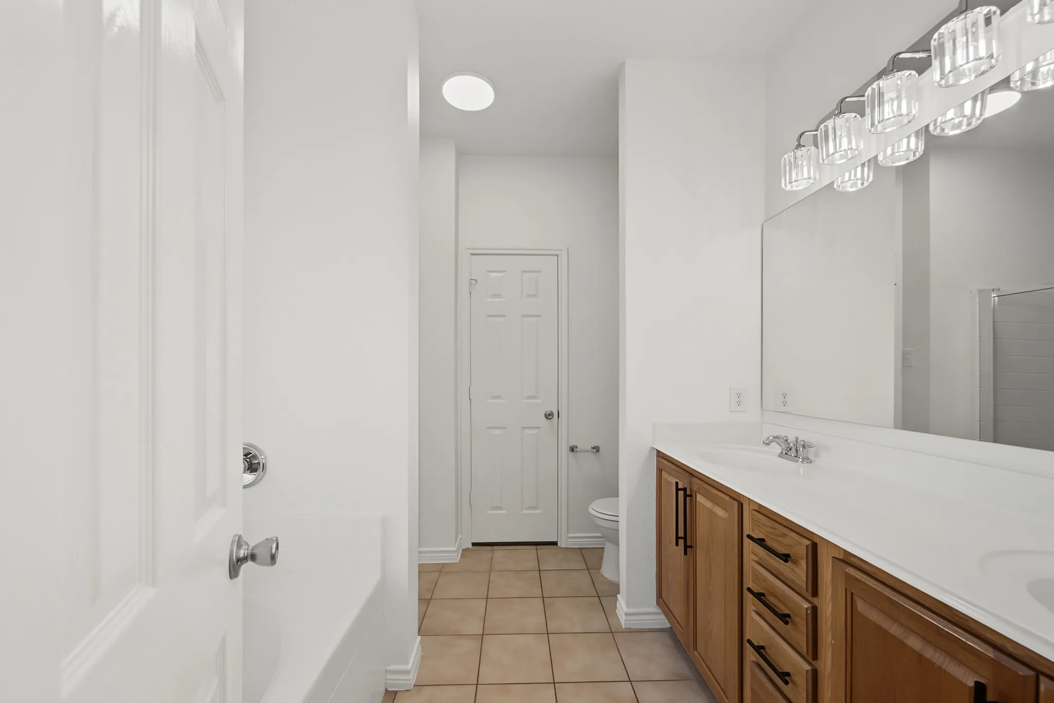 Double vanity with wood-finish cabinetry, white countertop, and integrated sinks