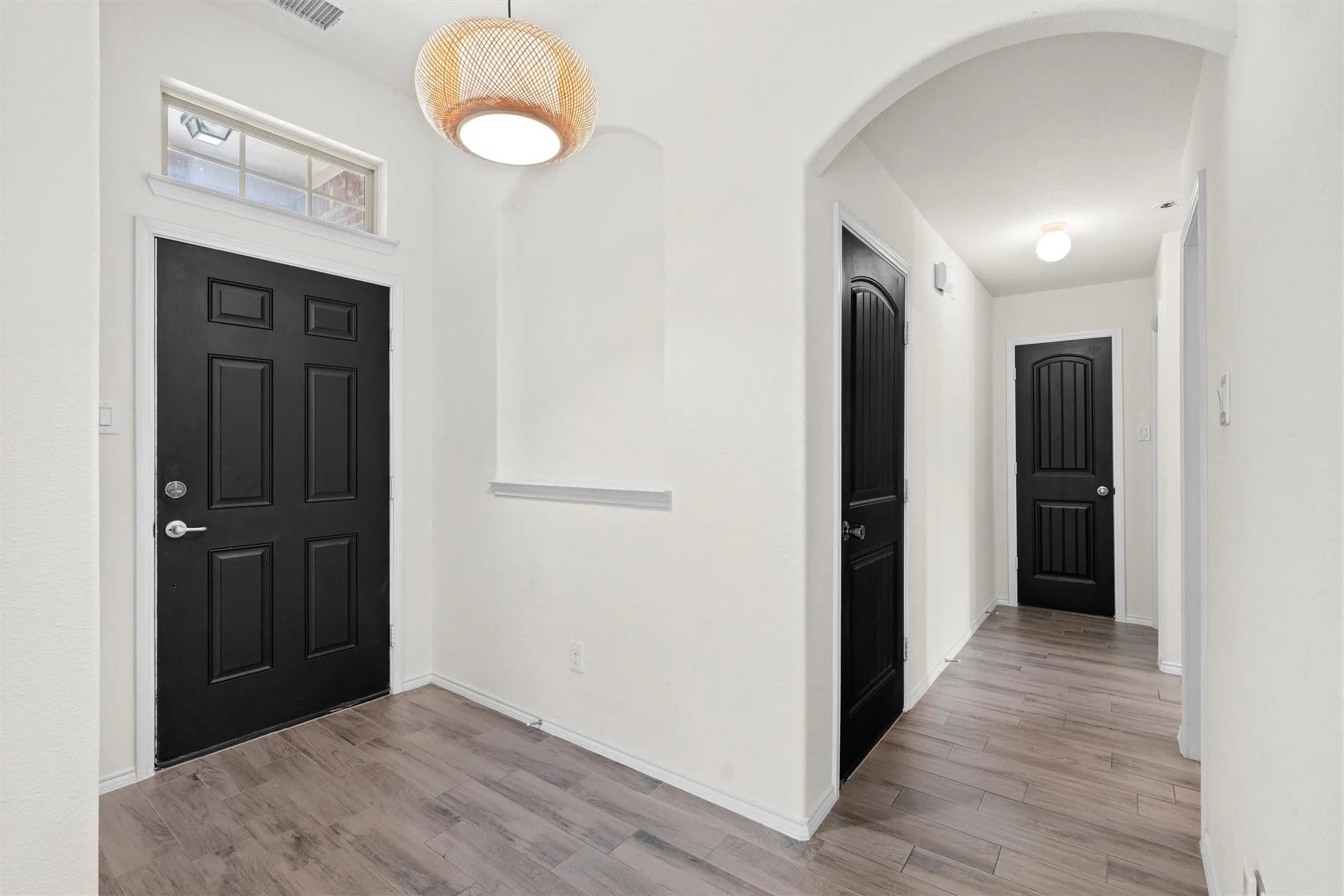 Talk about a grand entrance! The bright, wide-open foyer features stunning architectural archways, crisp contrast with sleek black doors, and a gorgeous statement light fixture that sets the vibe. Modern wood-look tile flooring flows effortlessly throughout the main living areas—perfect for style and easy cleaning.  #FoyerDecor #ModernInterior #FirstImpressions #WoodLookTile #RentalProperty