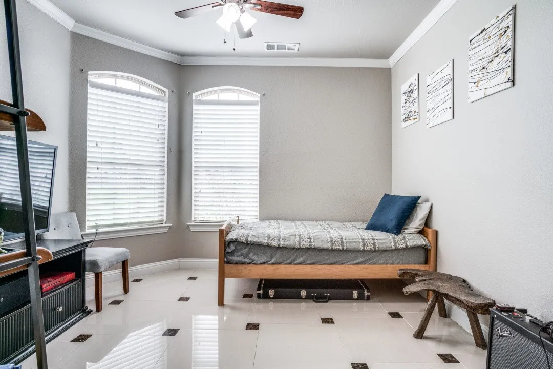 Neutral-toned room featuring a bay window with two arched top windows, white horizontal blinds, and crown molding
