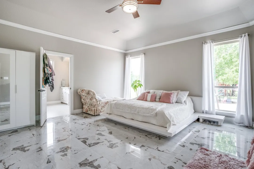Spacious room featuring polished tile flooring, two large windows, a vaulted ceiling, and crown molding