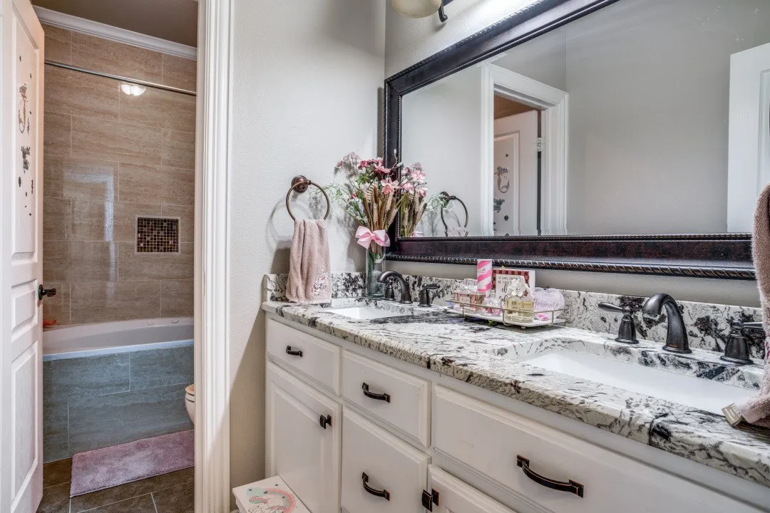 Double vanity with granite countertop, integrated sinks, and dark bronze hardware