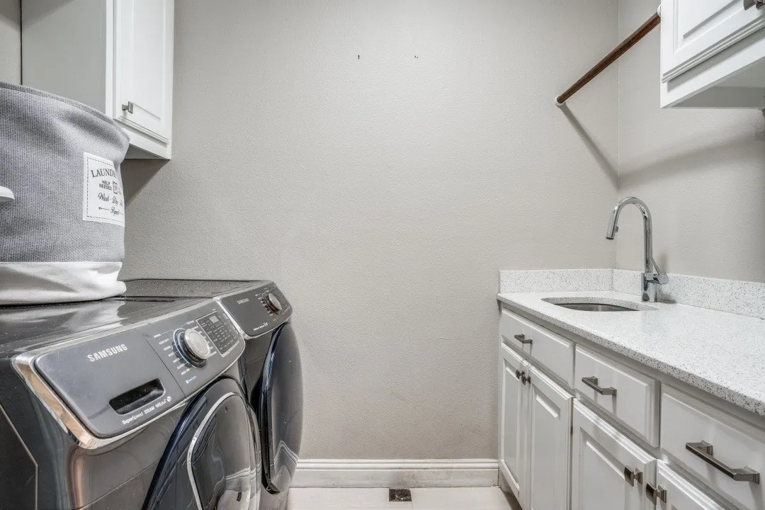 Laundry area featuring a utility sink, white cabinetry, a light-colored countertop, and a clothes hanging rod