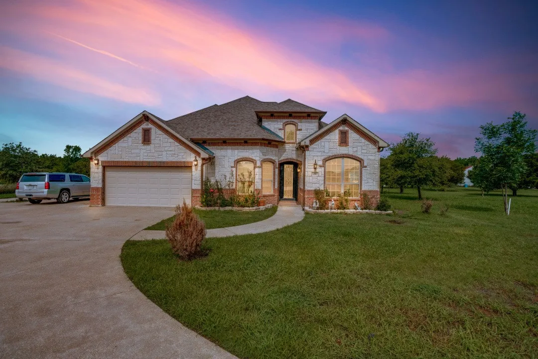 Stone and brick facade residence featuring an arched entry, multiple gables, and a two-car garage