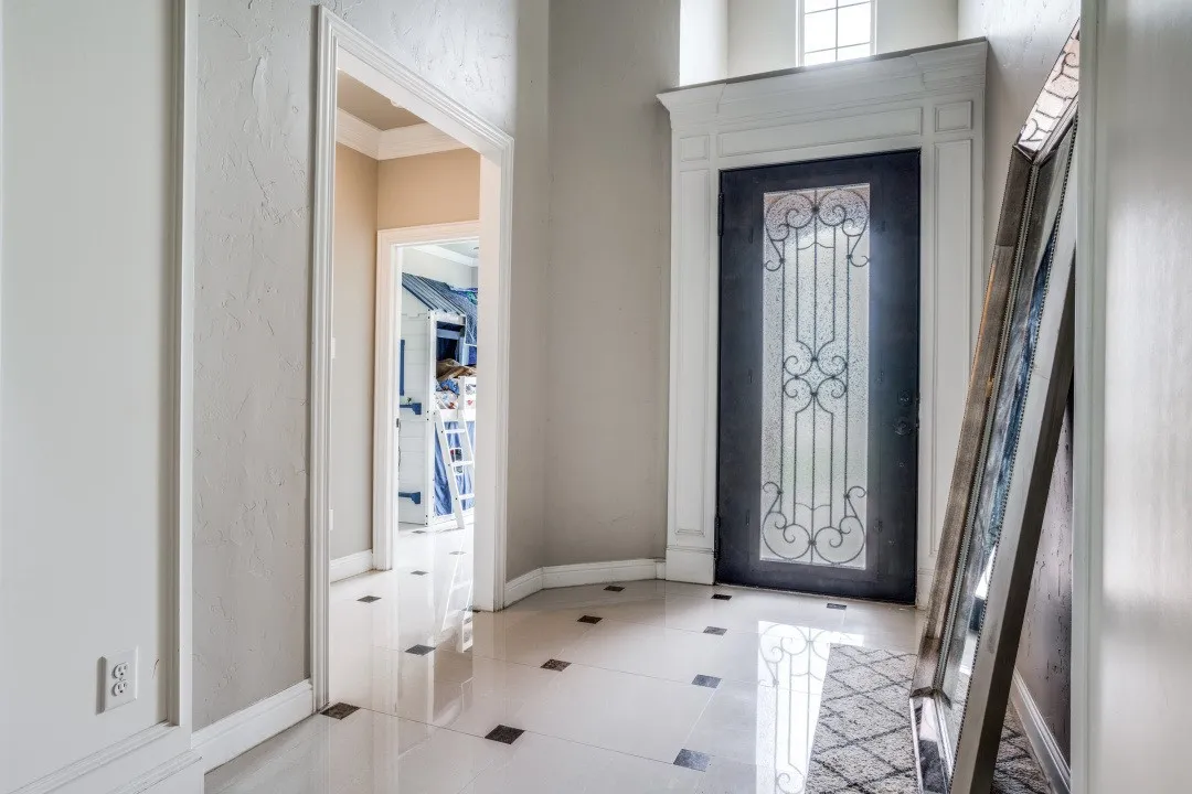 Entryway featuring a decorative glass-paned door with wrought iron detailing, a transom window, and white trim