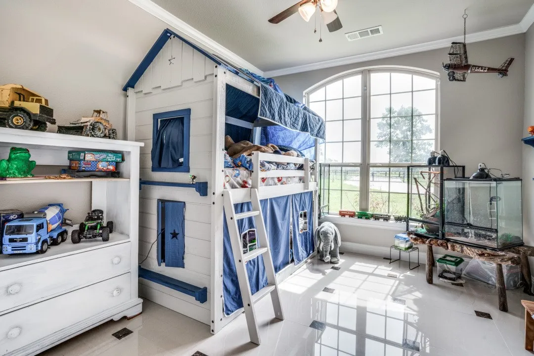Spacious room featuring a large arched window with grid detailing, polished tile flooring, and crown molding
