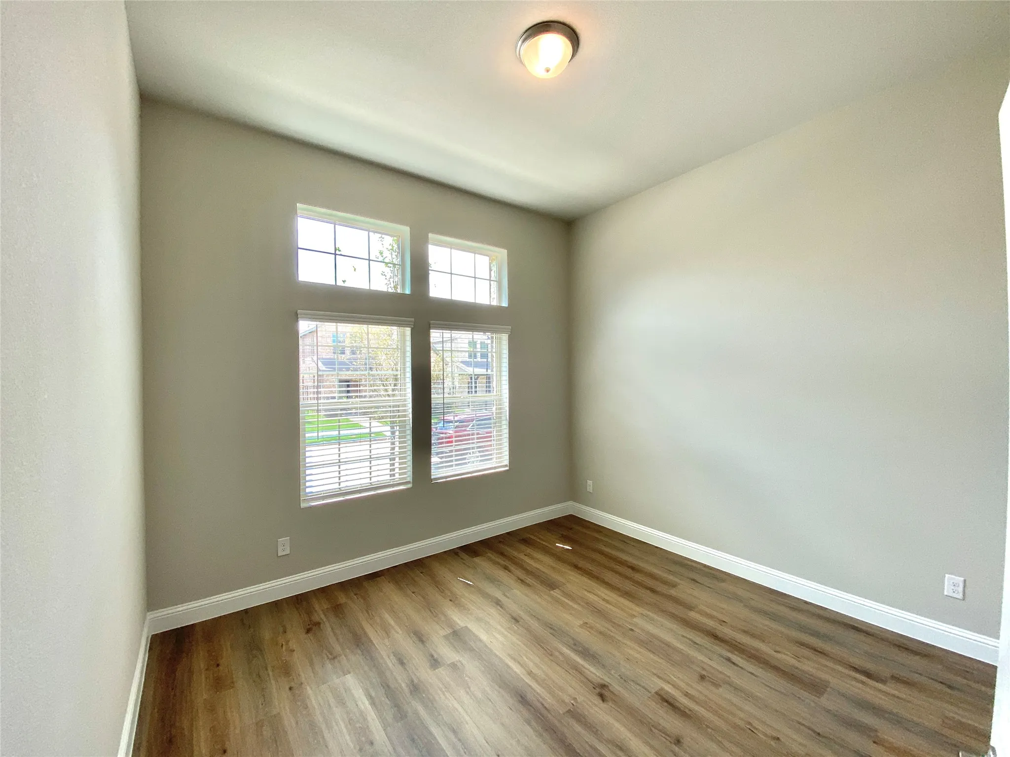 Interior room featuring wood-finish flooring, neutral wall tones, and white baseboards
