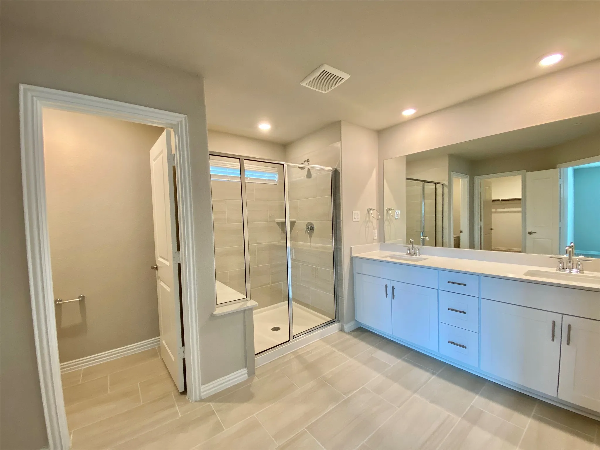 Bathroom featuring a dual vanity with white cabinetry, light-toned countertop, and chrome fixtures