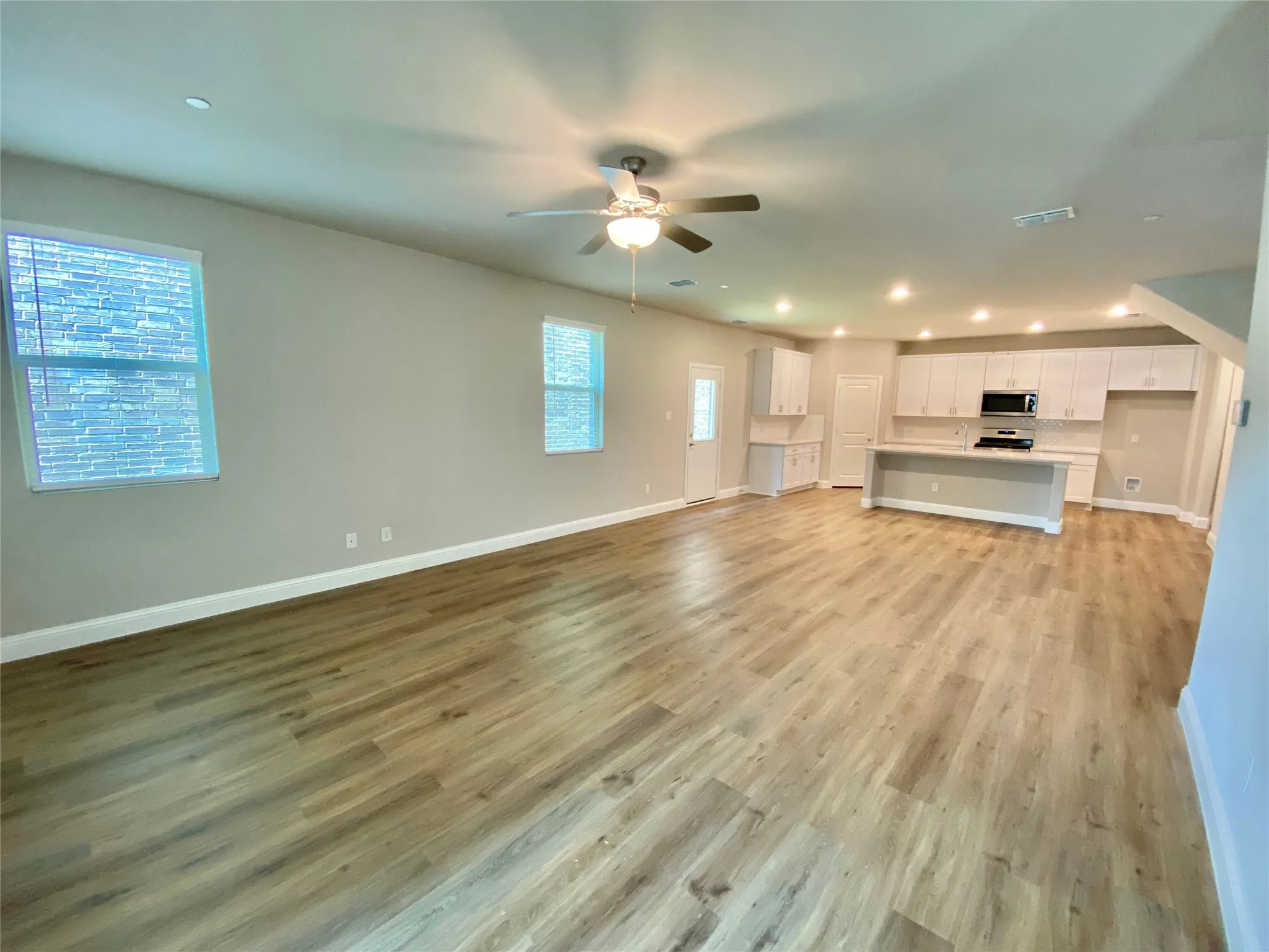 Open-concept living space featuring wood-finish flooring, recessed lighting, and a ceiling fan