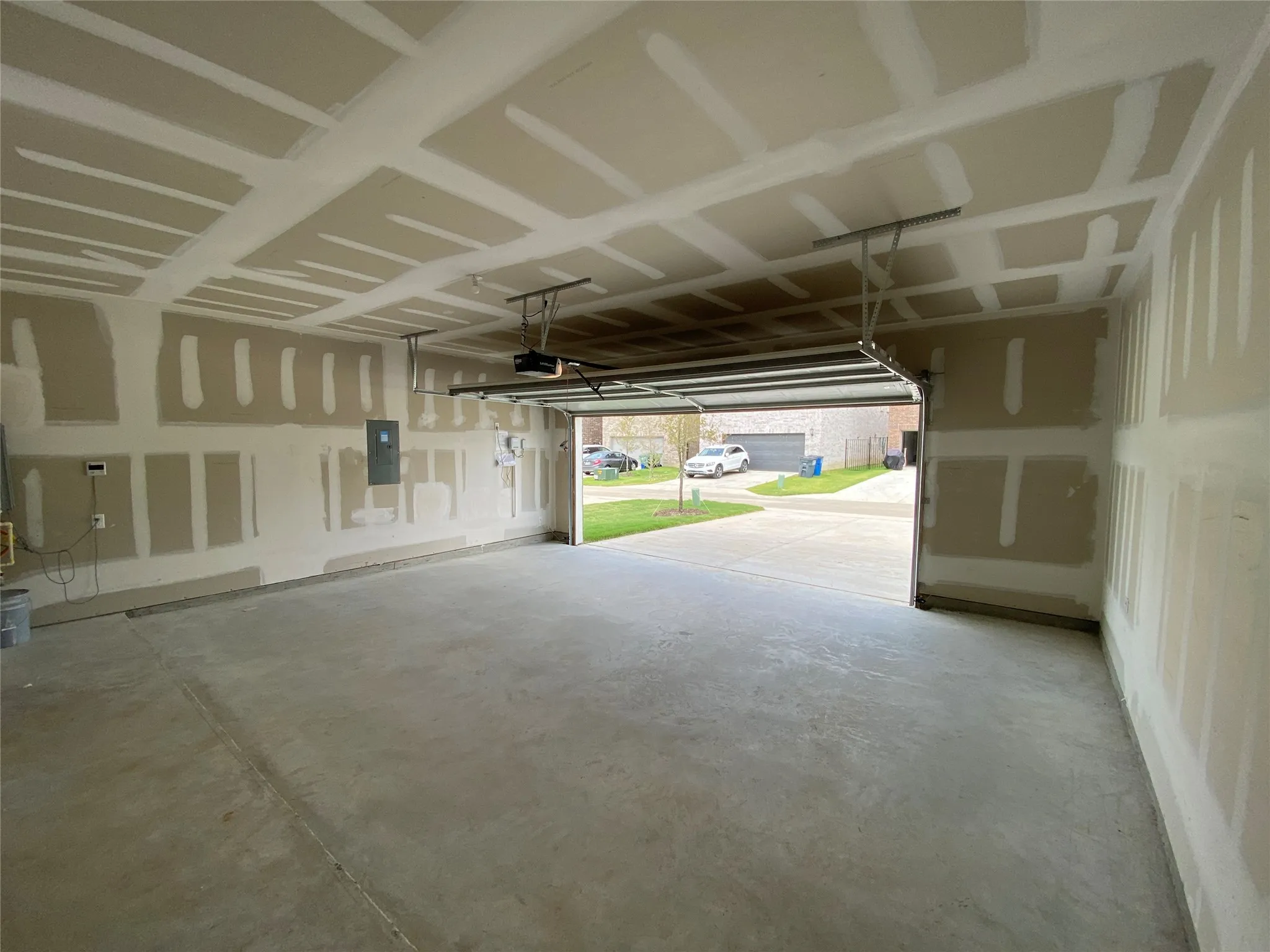 Spacious two-car garage with concrete flooring and exposed drywall