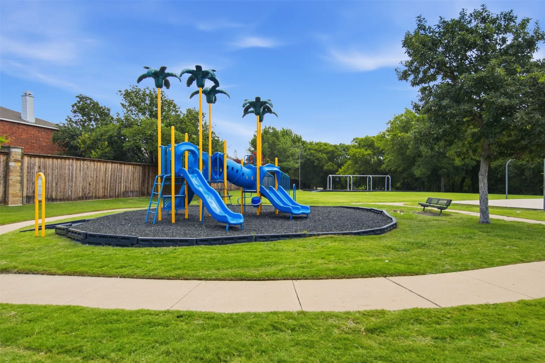 Community playground featuring a multi-level play structure with slides and palm tree accents