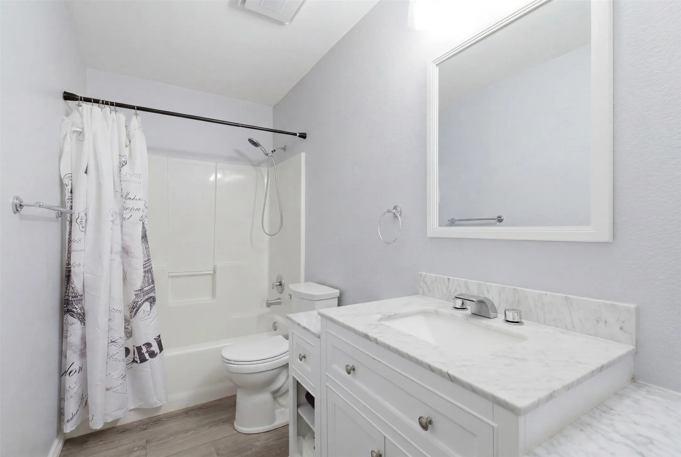 White vanity with a single basin sink, chrome faucet, and stone countertop