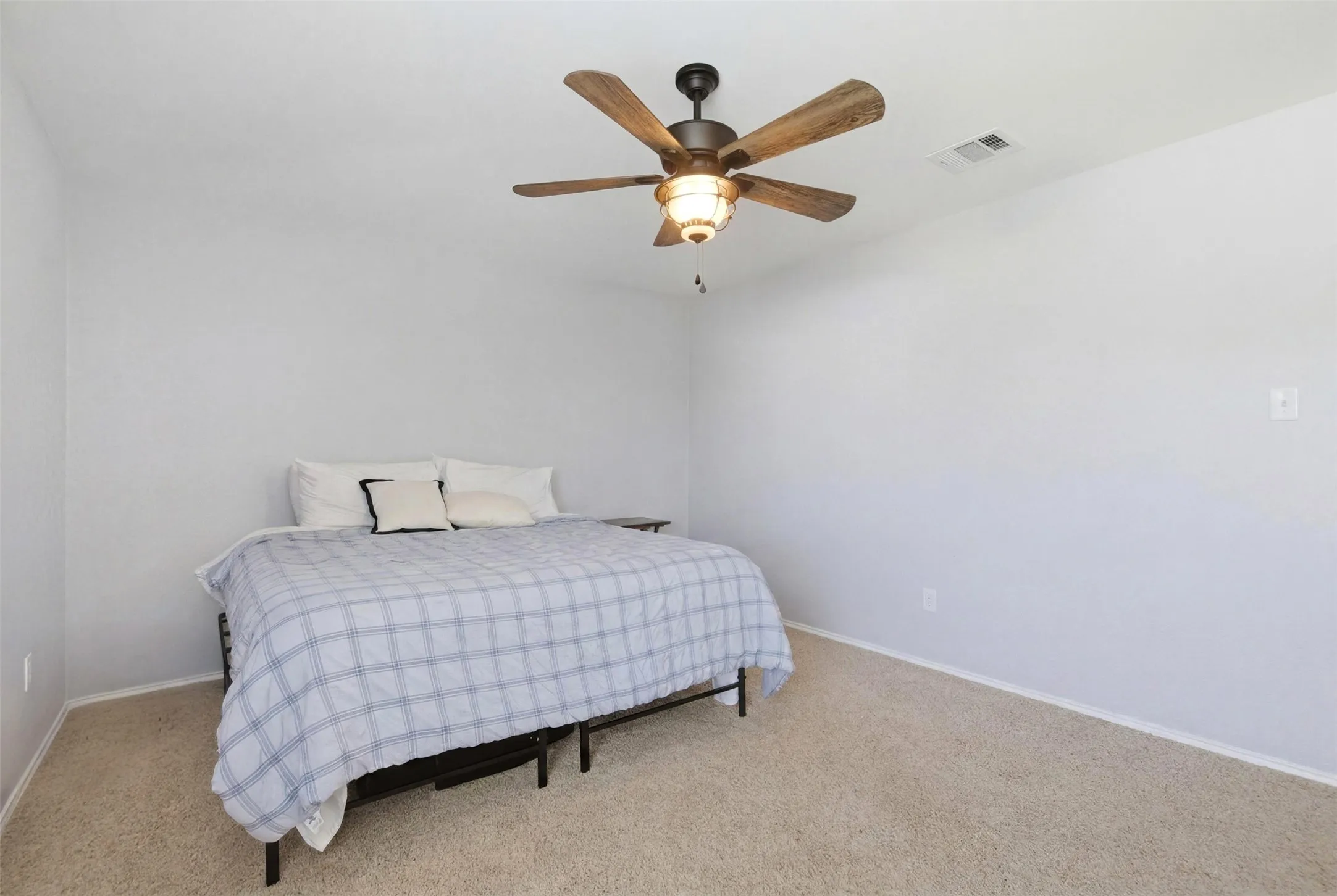 Bedroom featuring a ceiling fan with wood-finish blades, light gray walls, and carpet flooring