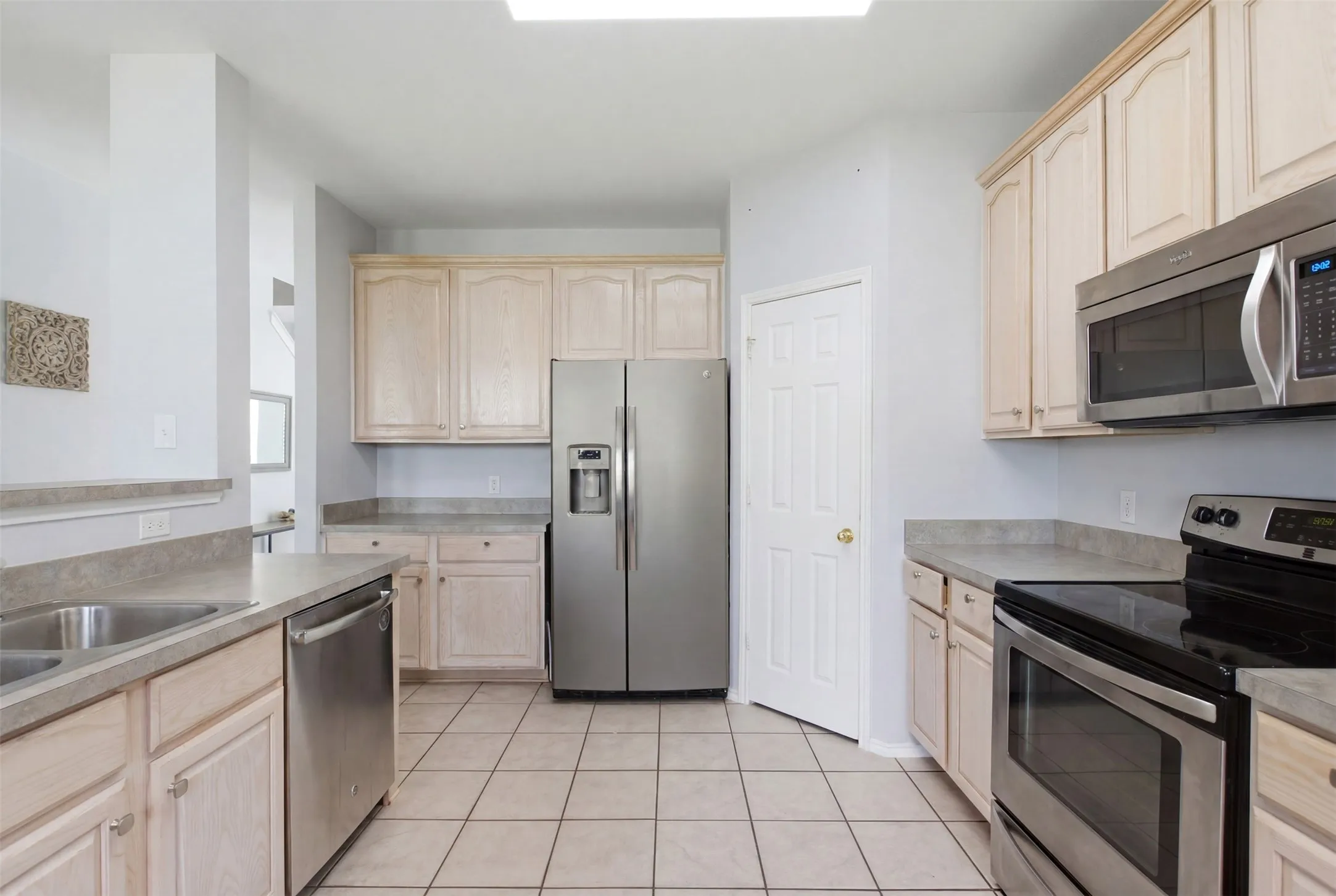 Kitchen featuring light wood cabinetry, stone-finish countertops, and stainless steel appliances