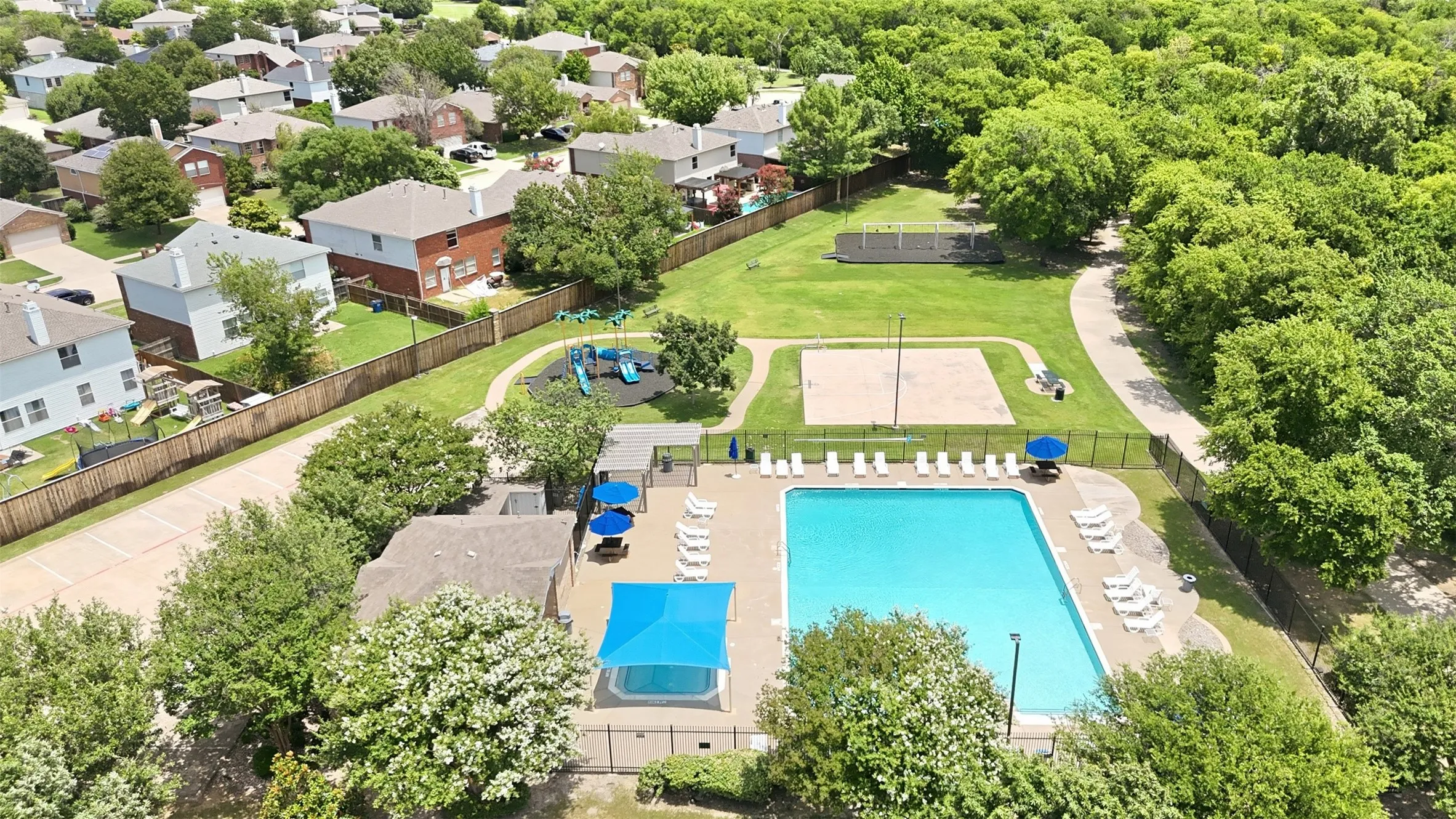 Community amenities featuring a swimming pool with surrounding lounge seating, a separate shaded spa, a sand volleyball court, and a children's play area