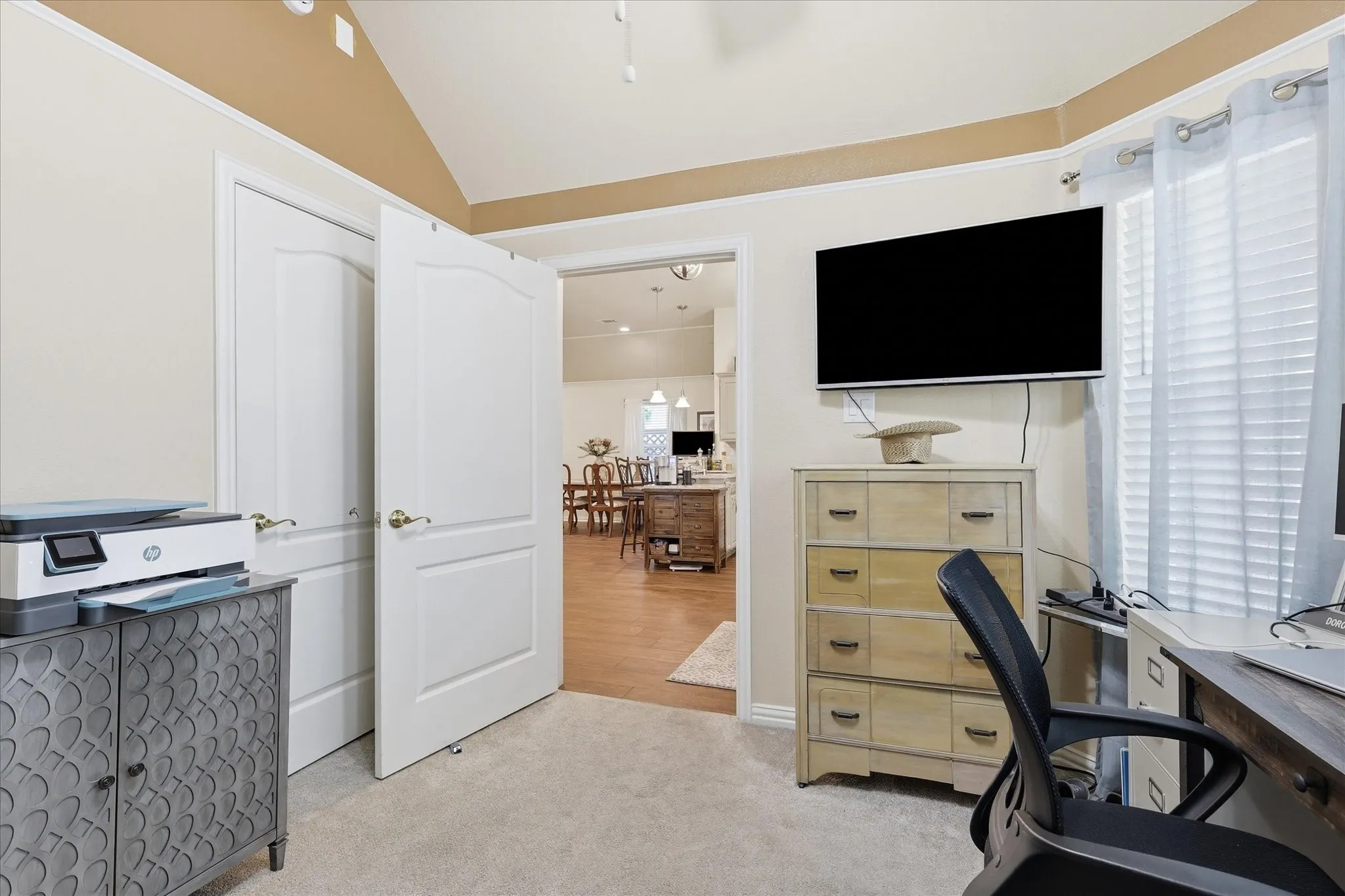 Carpeted room with a vaulted ceiling and a neutral wall color