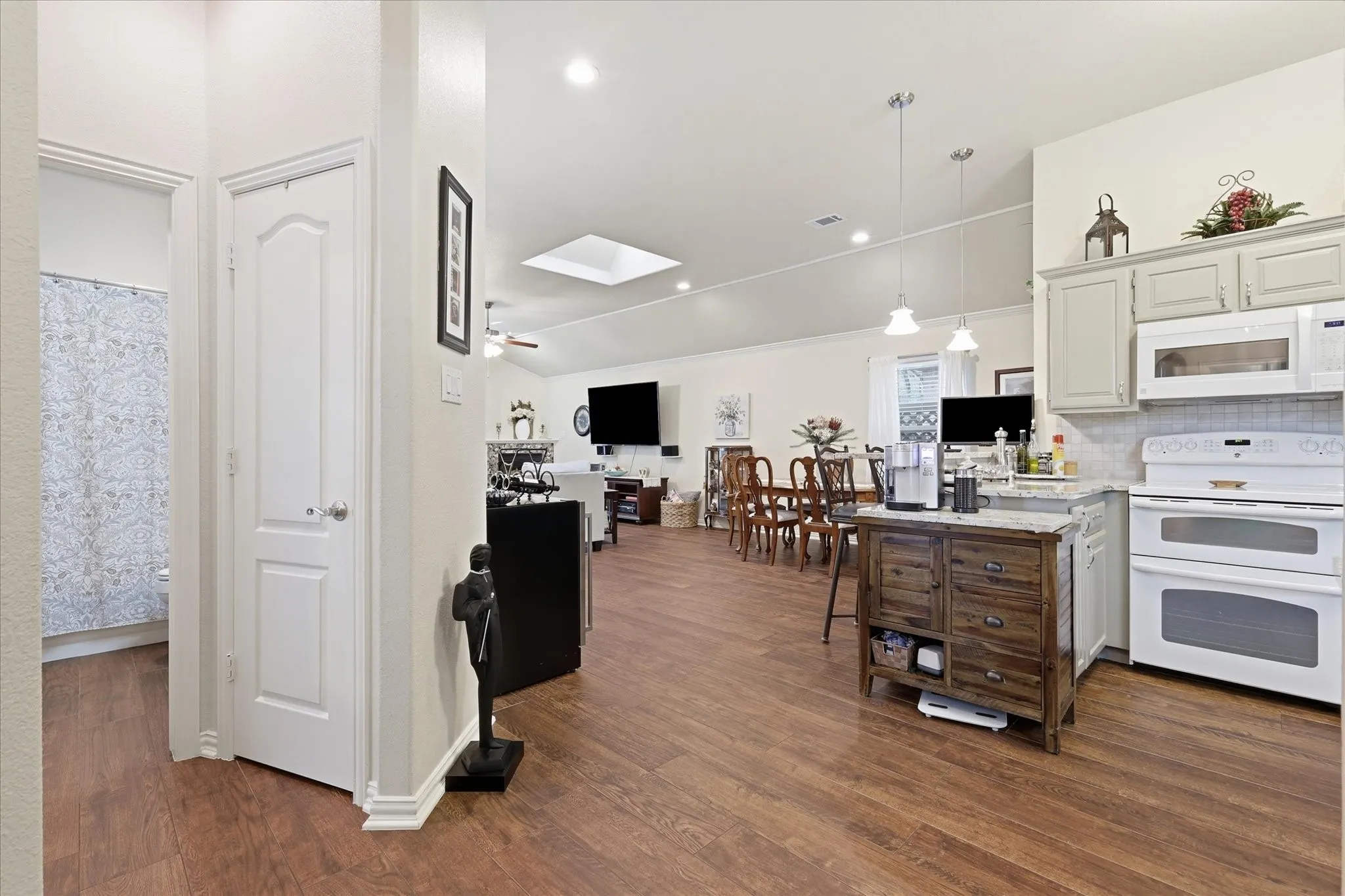 Open-concept living area with wood-finish flooring, vaulted ceilings, and a skylight