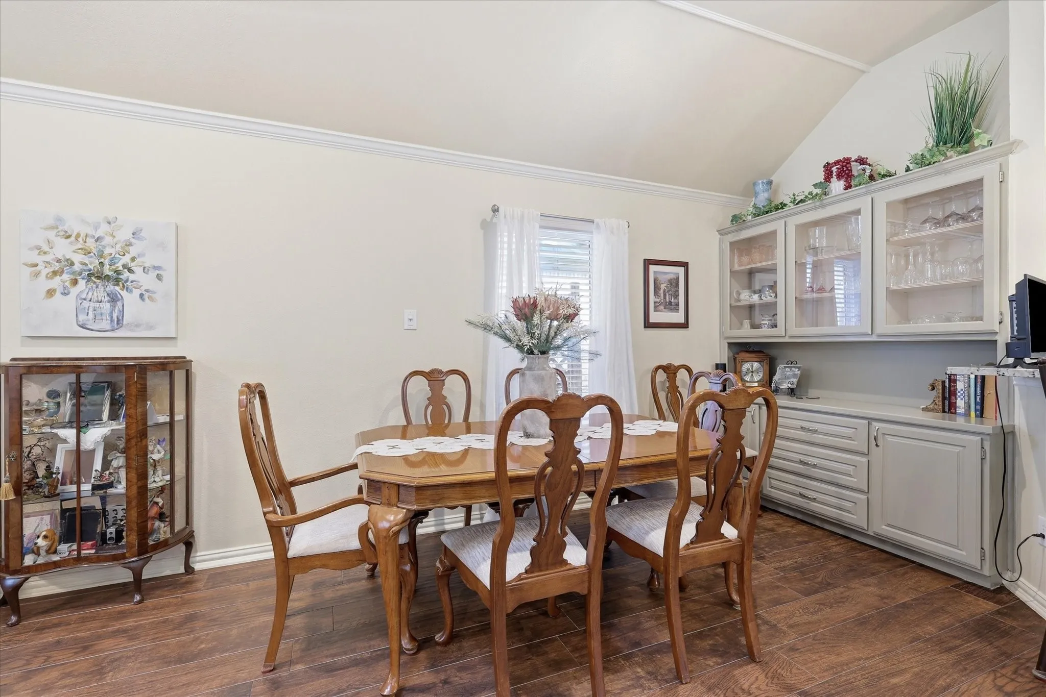 Vaulted ceiling with crown molding above wood-finish flooring