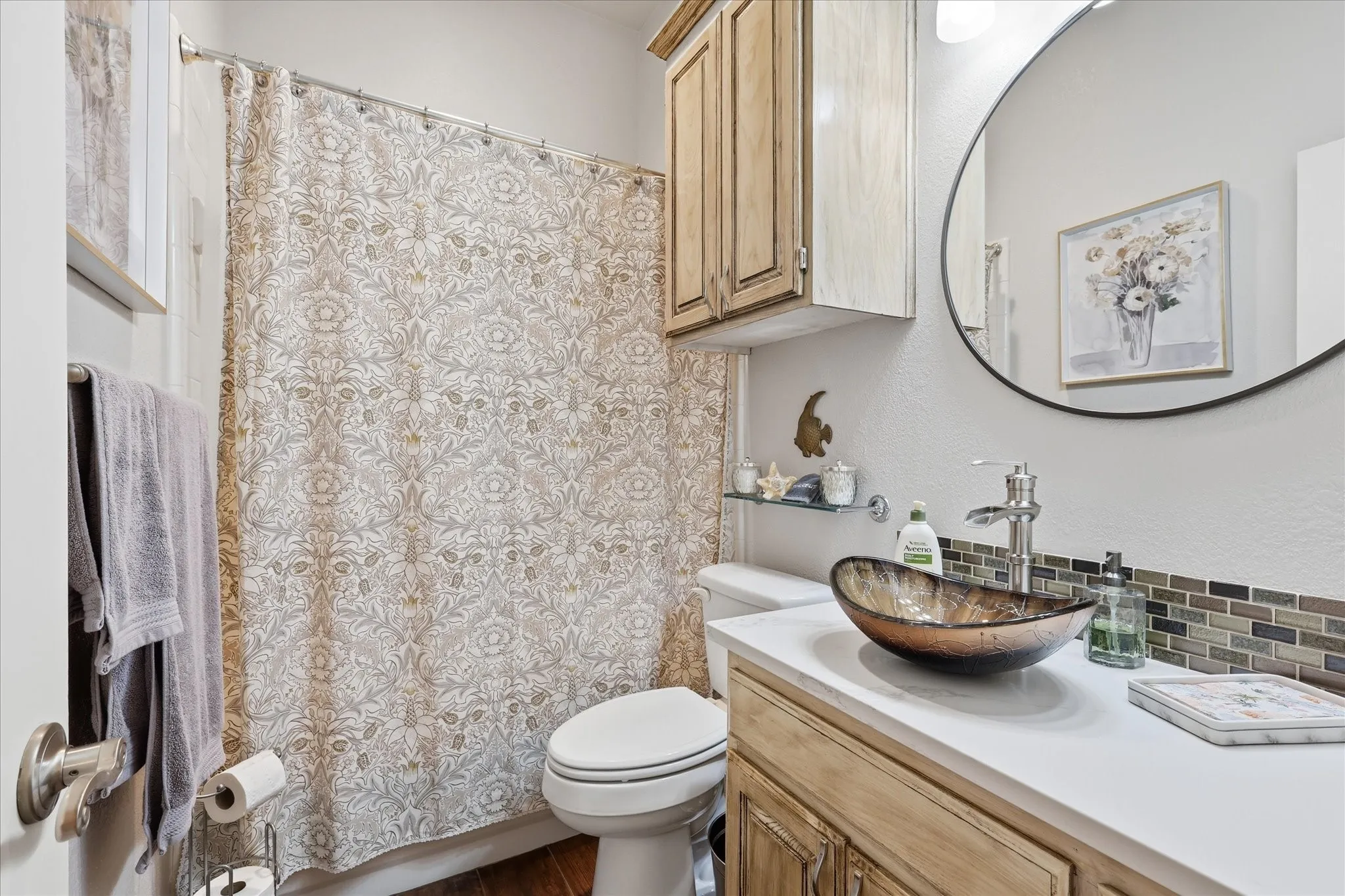 Bathroom vanity with a vessel sink, white countertop, and tile backsplash