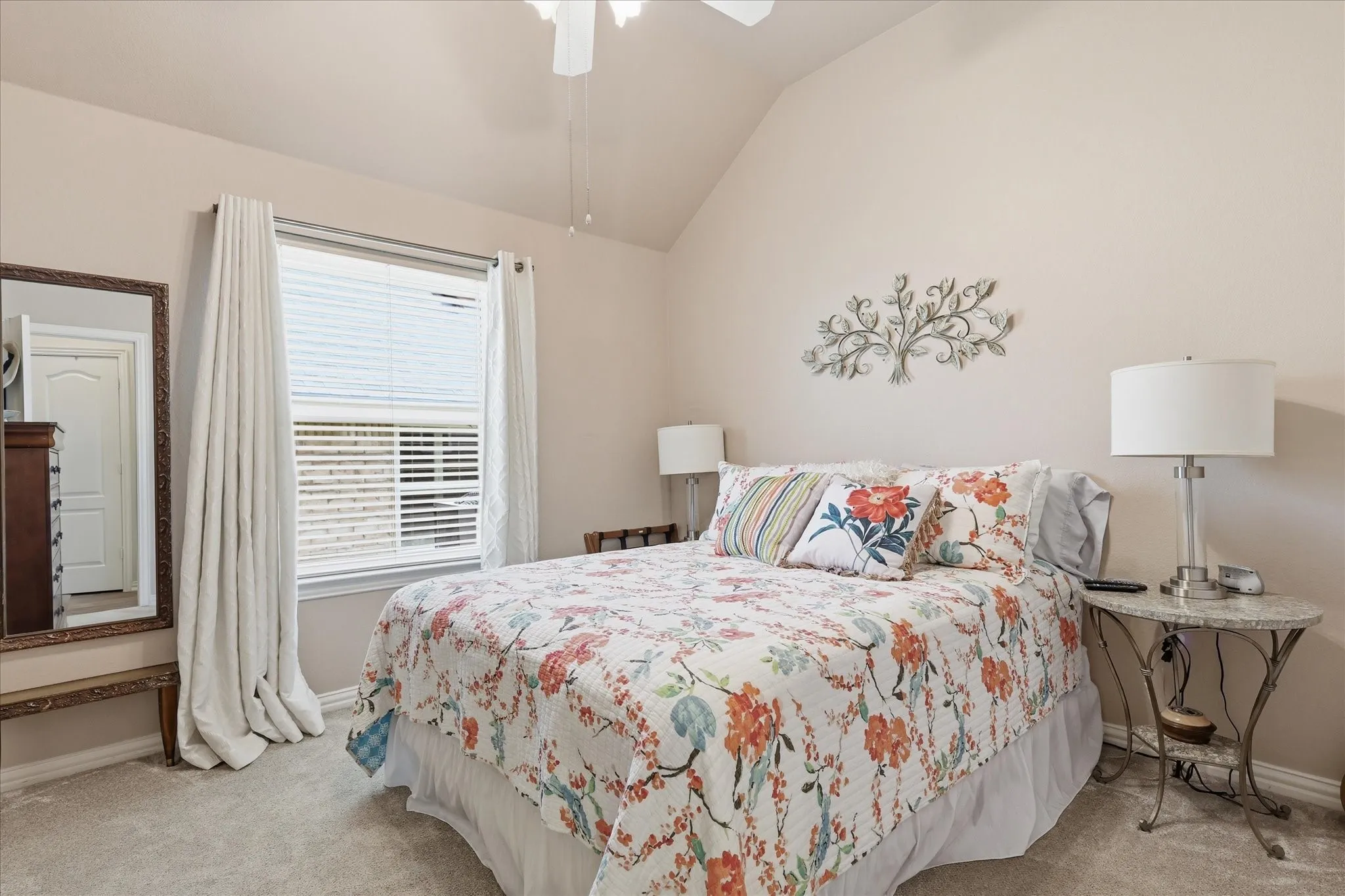 Carpeted bedroom featuring a vaulted ceiling and a ceiling fan