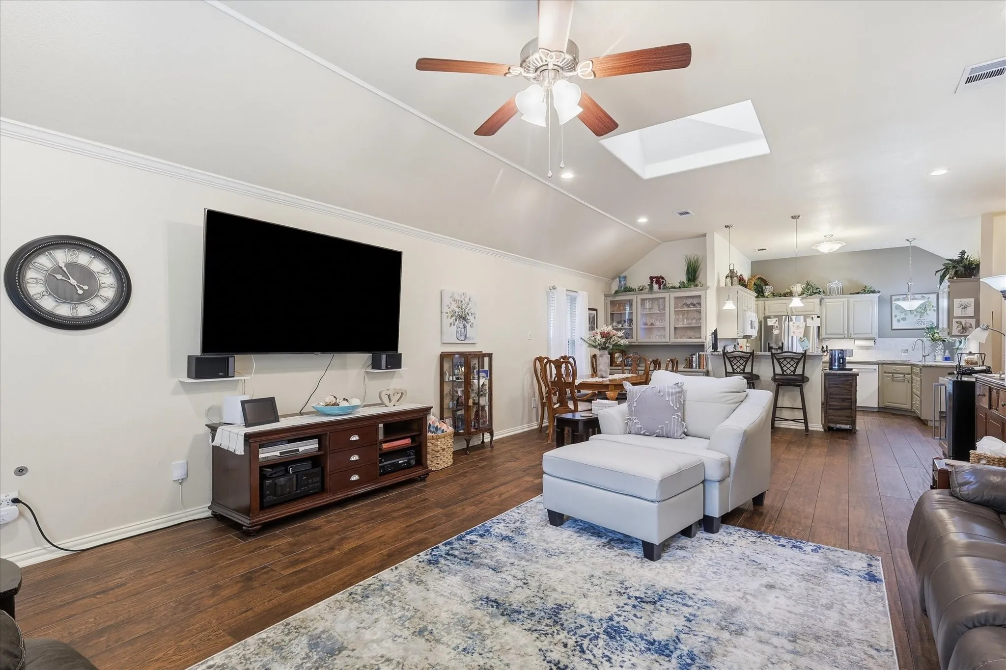 Open concept living area featuring vaulted ceilings, a skylight, and wood-finish flooring