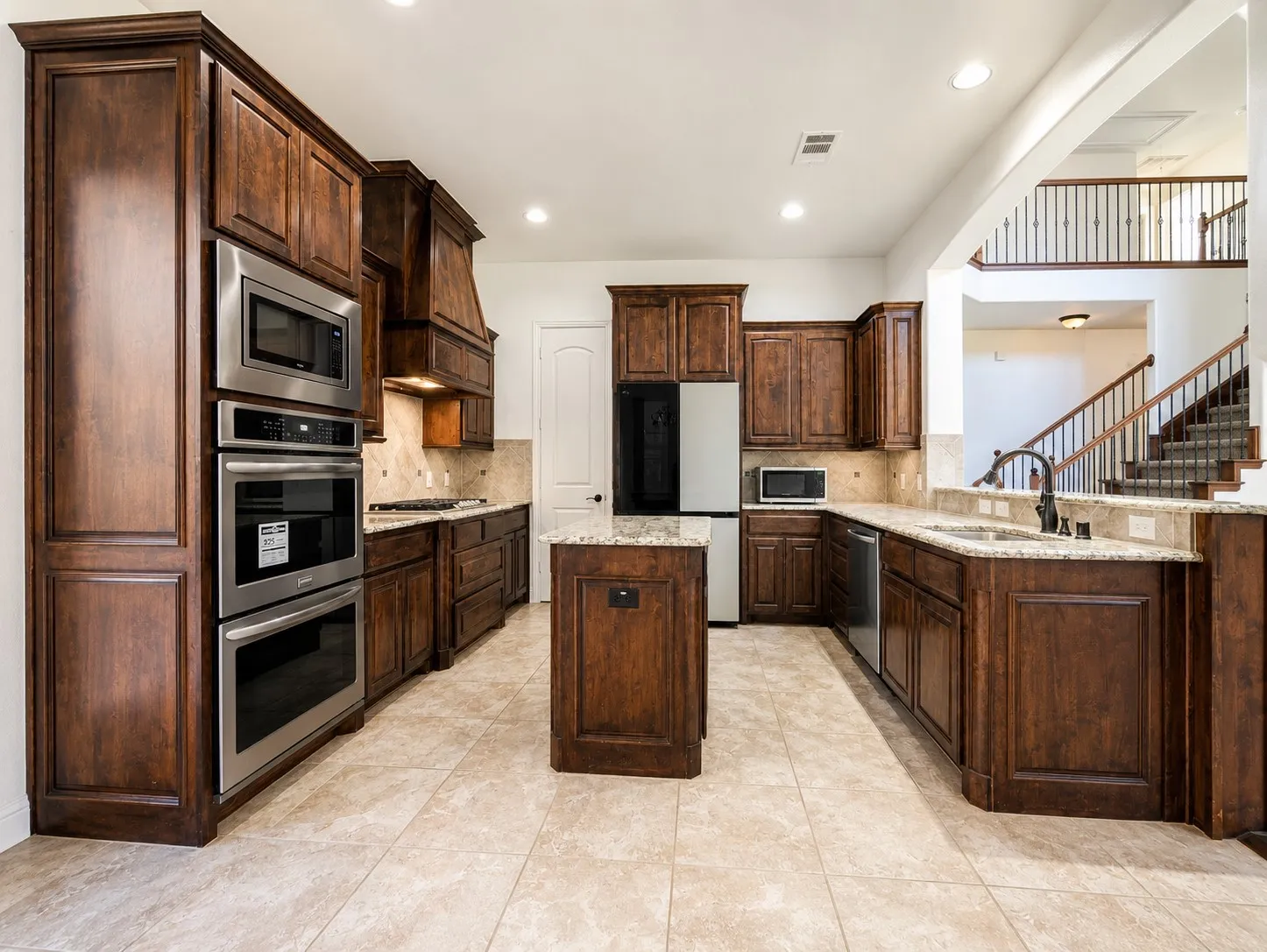 Kitchen featuring dark wood cabinetry, stainless steel double ovens, and a built-in microwave