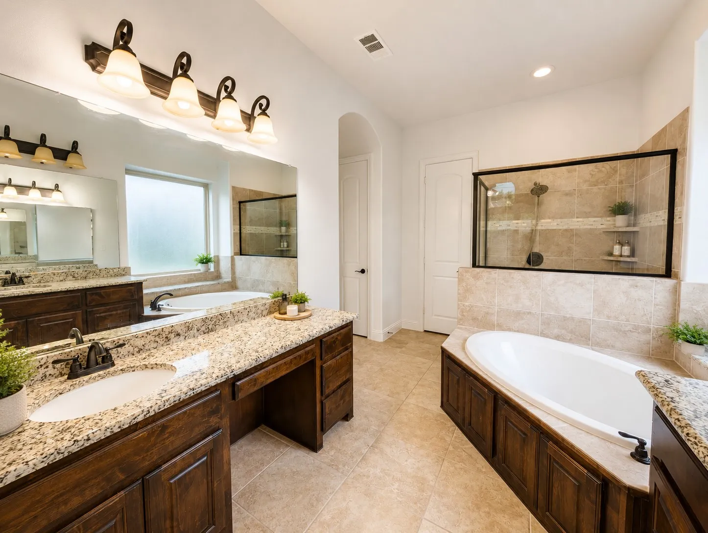Spacious bathroom featuring dual granite-topped vanities, a built-in soaking tub, and a separate glass-enclosed shower